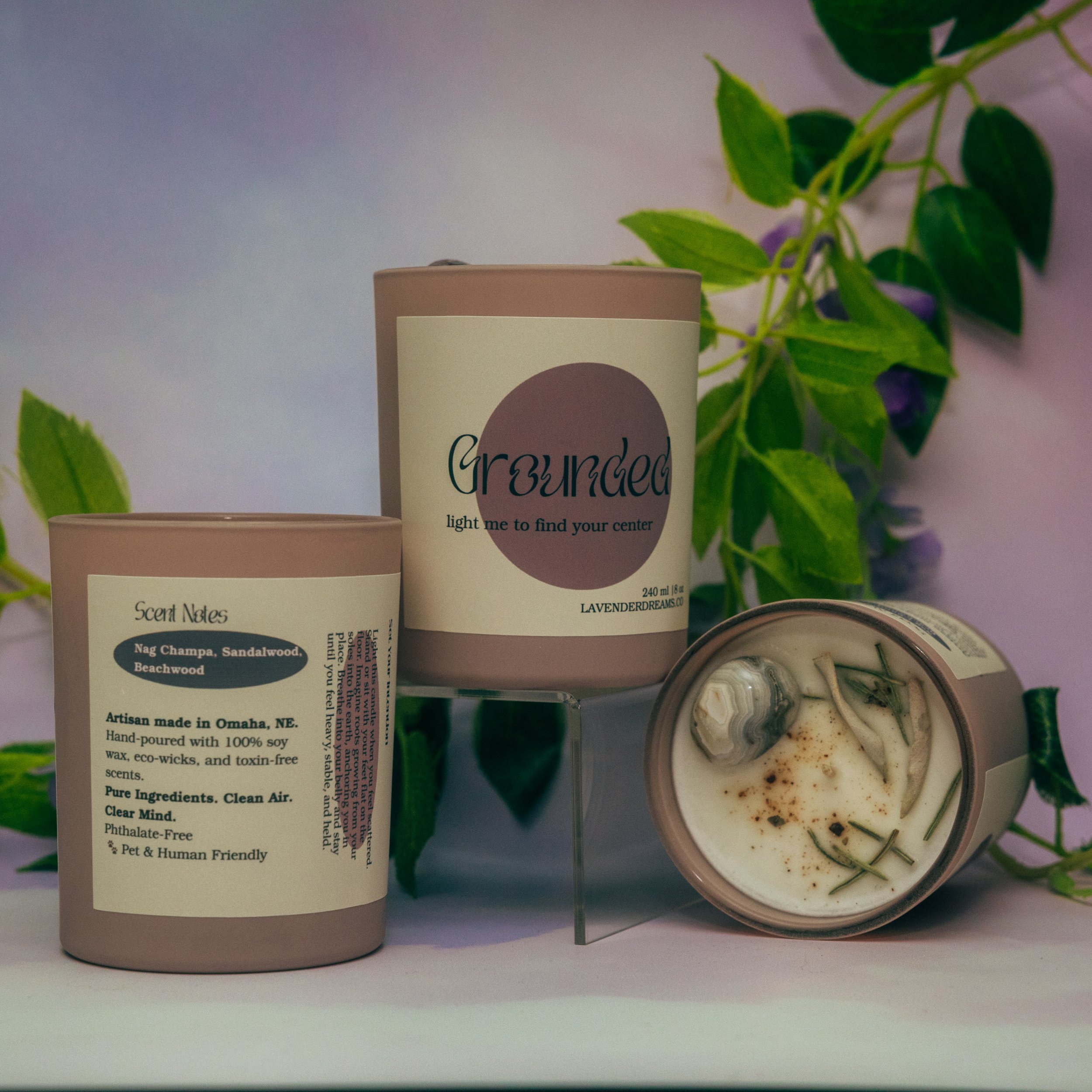 Close-up of two skincare or beauty product containers, with plants in the background.