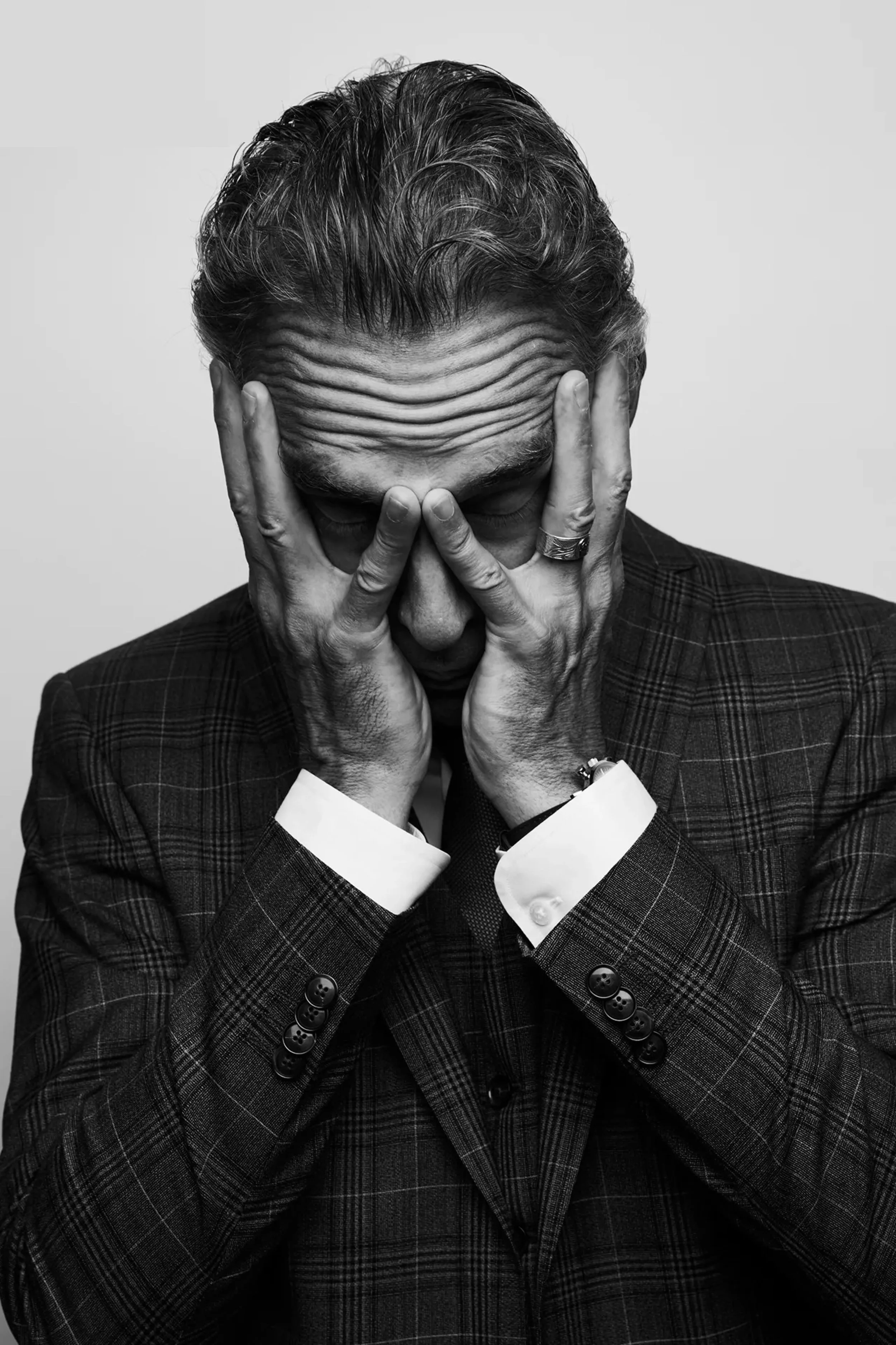 A boy looking at the camera, reflected in a mirror with broken pieces. The reflection shows his face and part of his upper body, and water droplets are visible on the surface.