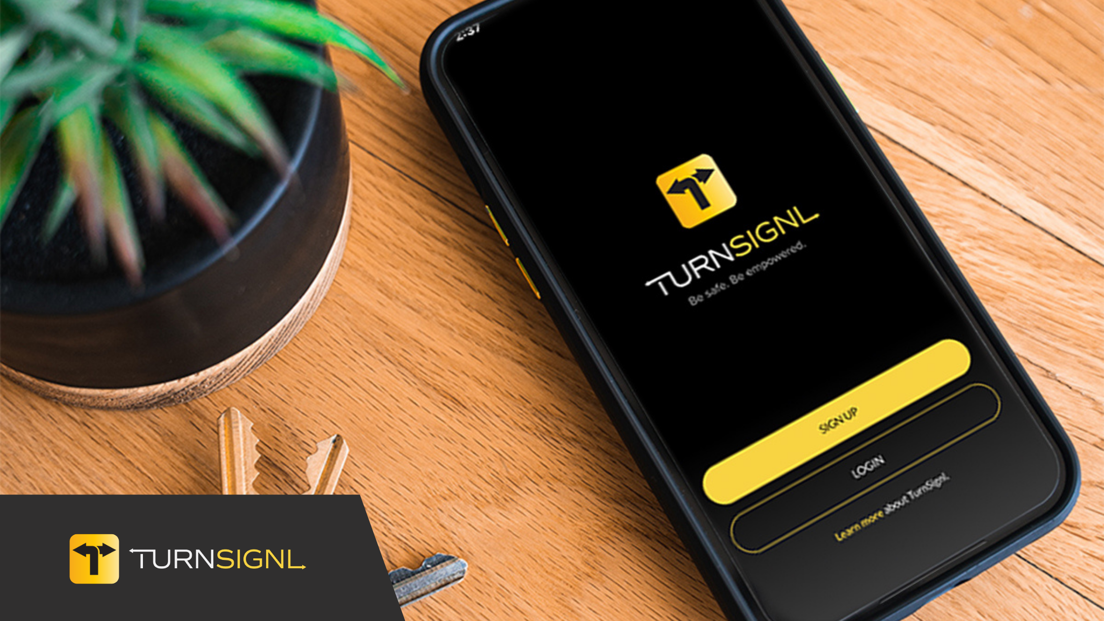 TurnSignl app home screen on phone, next to potted plant and keys on desk