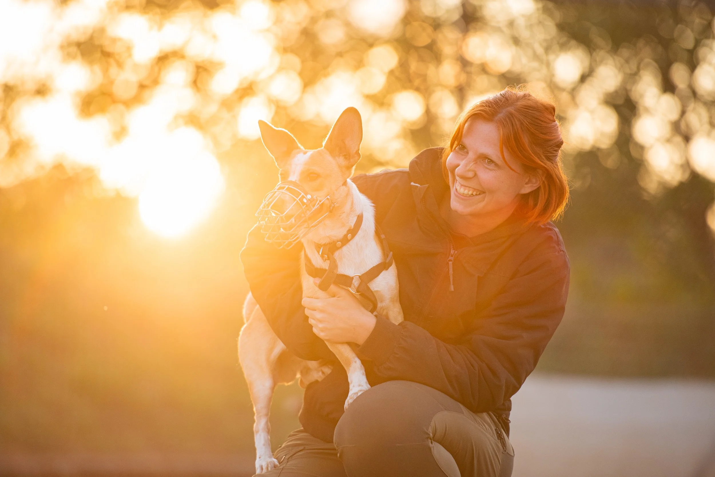 Hundetrainerin Hannah Rohde mit einem Terrier auf dem Arm, der einen Maulkorb trägt.