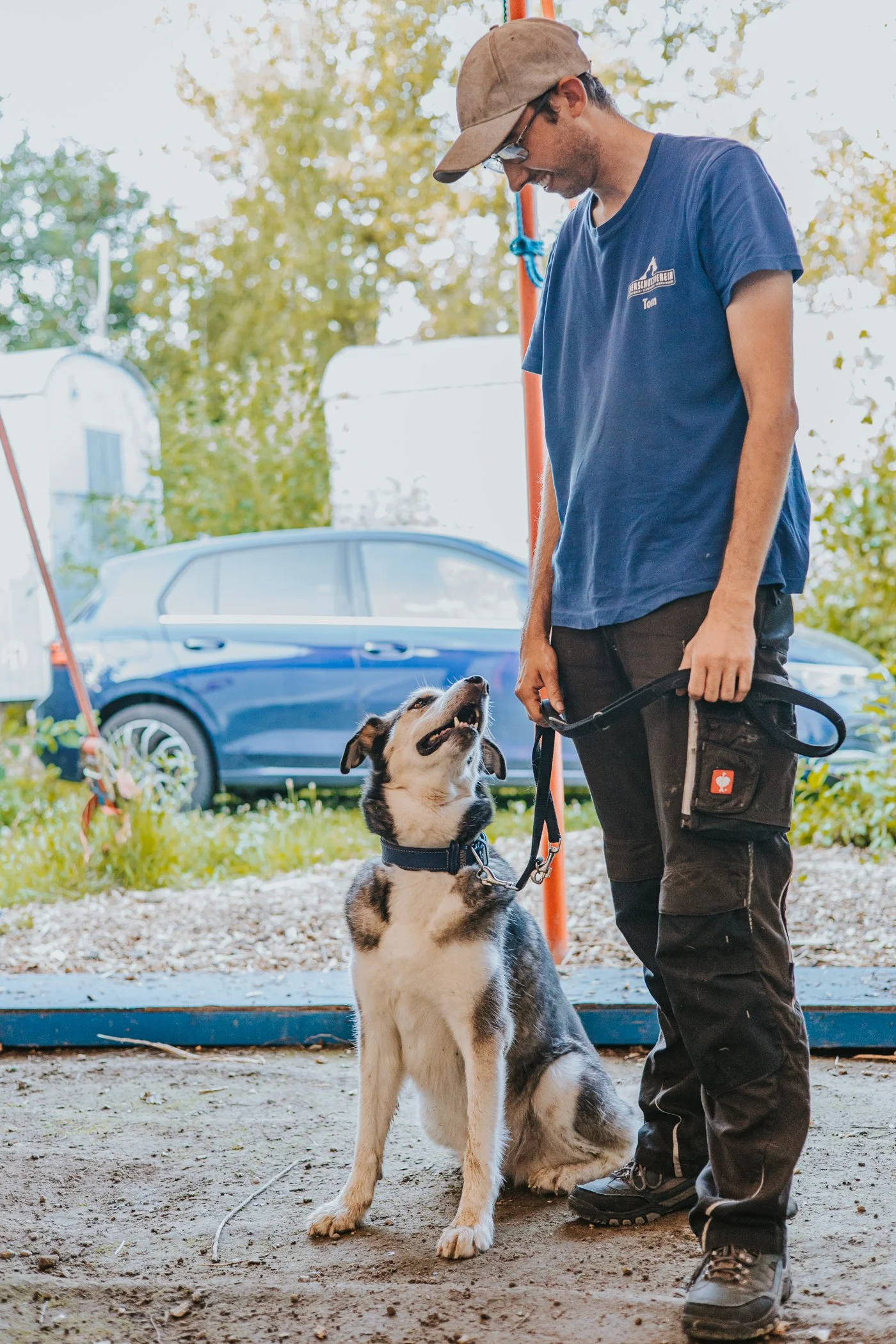 Tom Jankowski mit seinem Husky Damian. Der Husky sitzt an lockerer Leine neben ihm und schaut aufmerksam zu seinem Menschen.