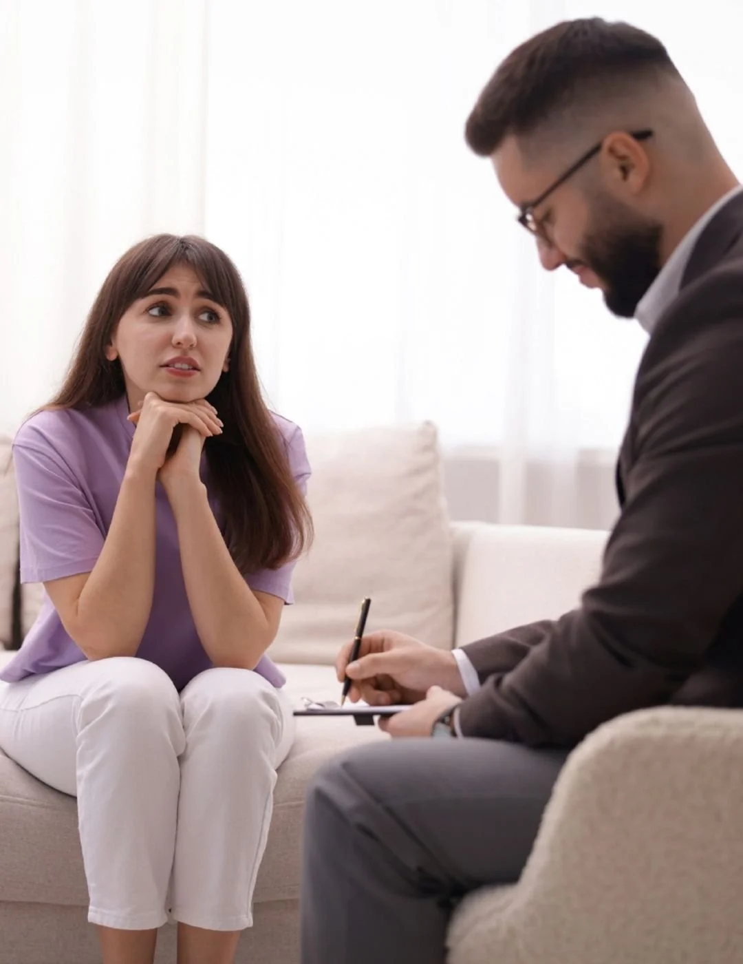 Young woman in a therapy session discussing mental health concerns with a professional male psychologist.