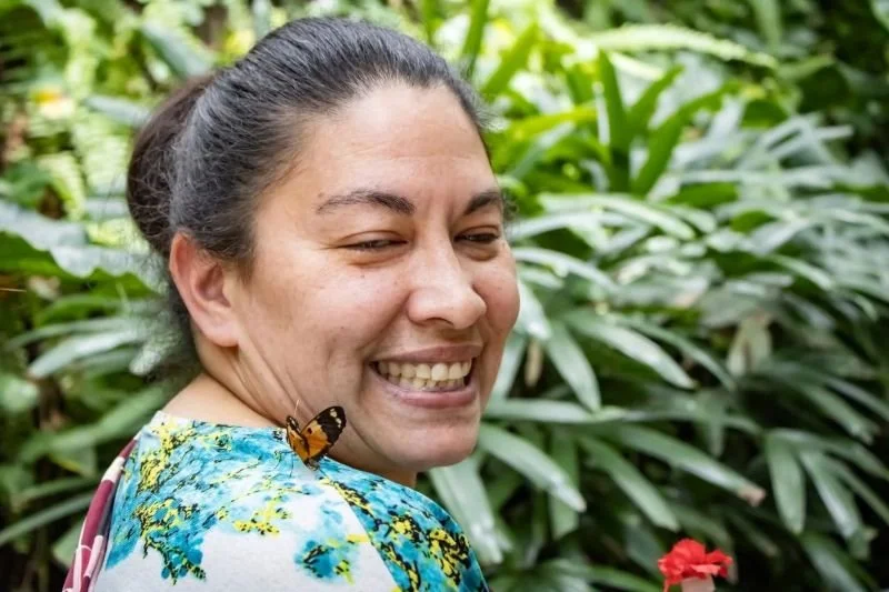 Older woman with bright smile and a butterfly on her shoulder
