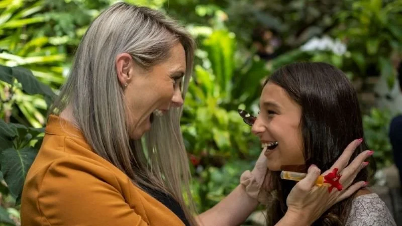 Mother excitedly looking at her young laughing daughter in the butterfly aviary