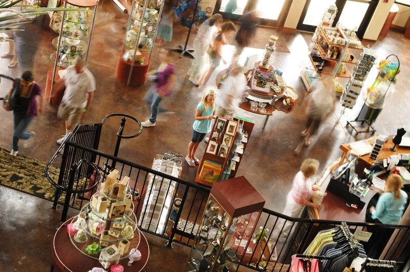 an over view shot of the gift shop with people shopping for various souvenirs