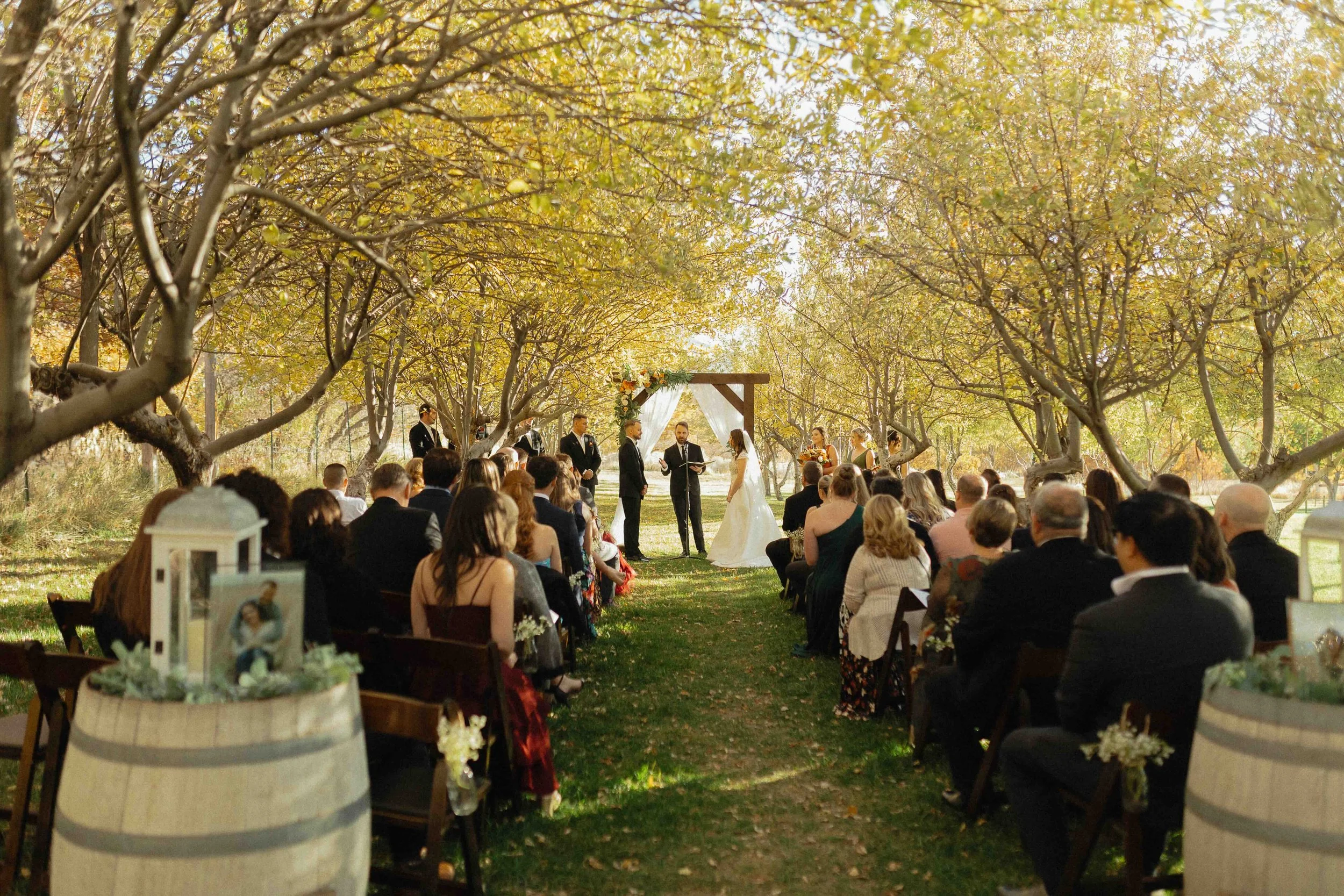 Bridal ceremony taking place in an orchard with yellow leaves in the background.