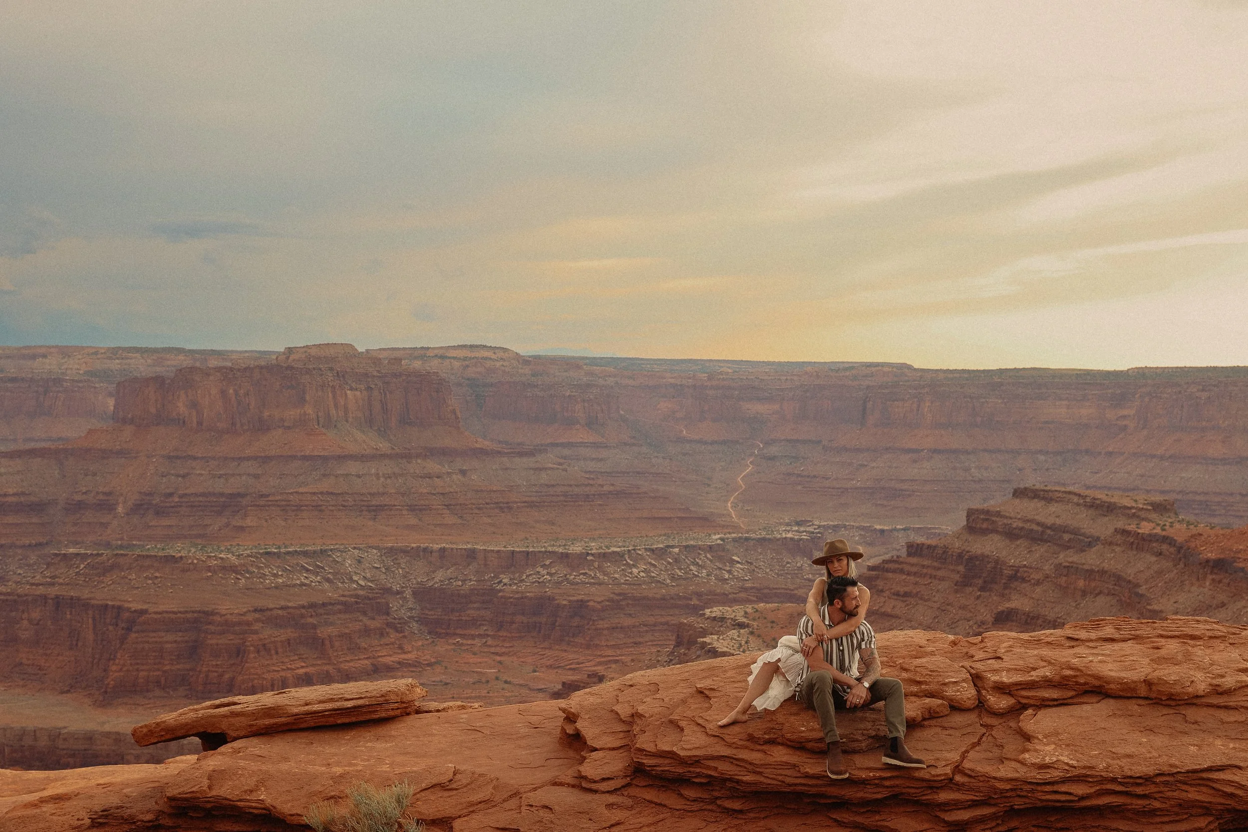 A Moab desert couple sitting on red stone with a red canyon in the background.