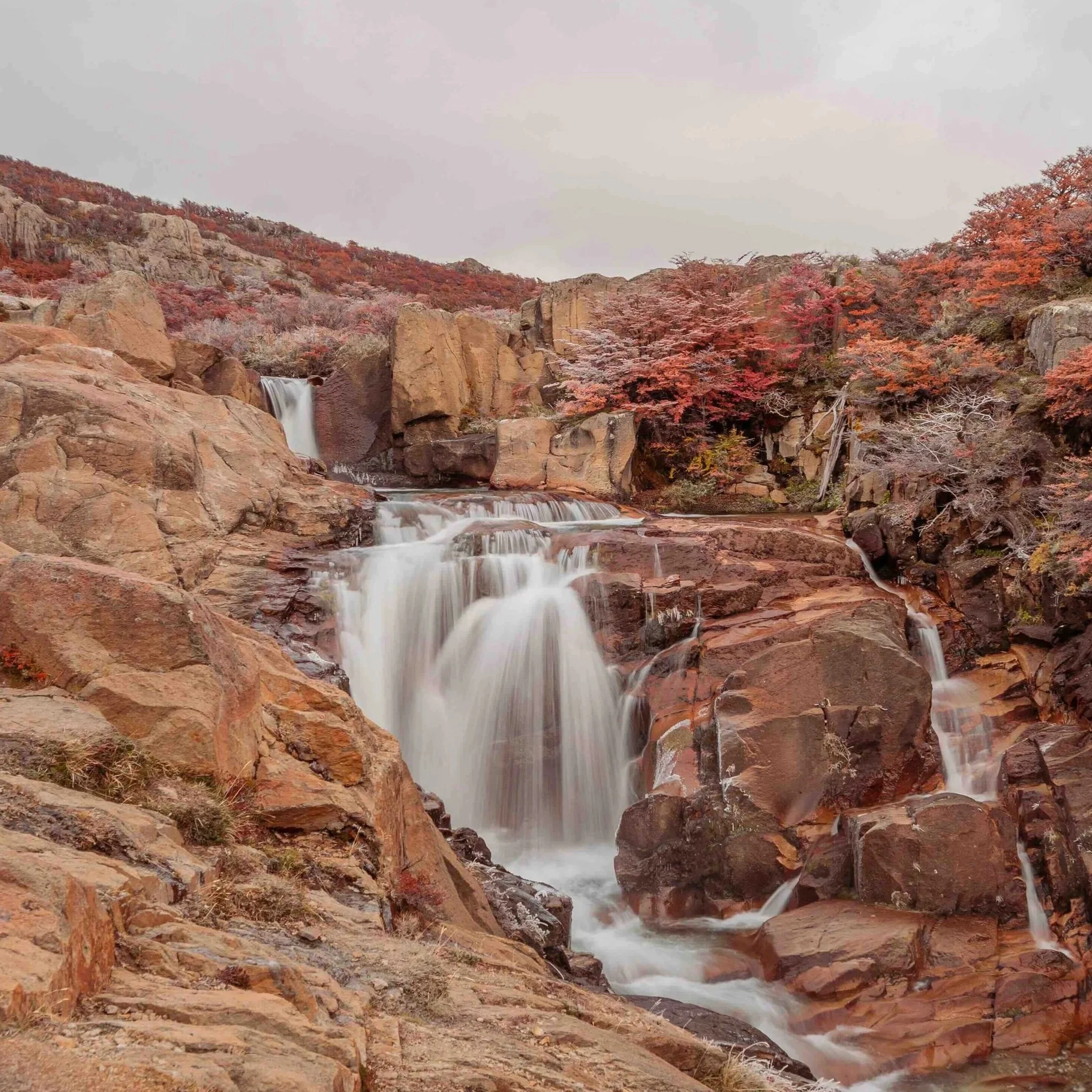 A waterfall in front of red rock background.