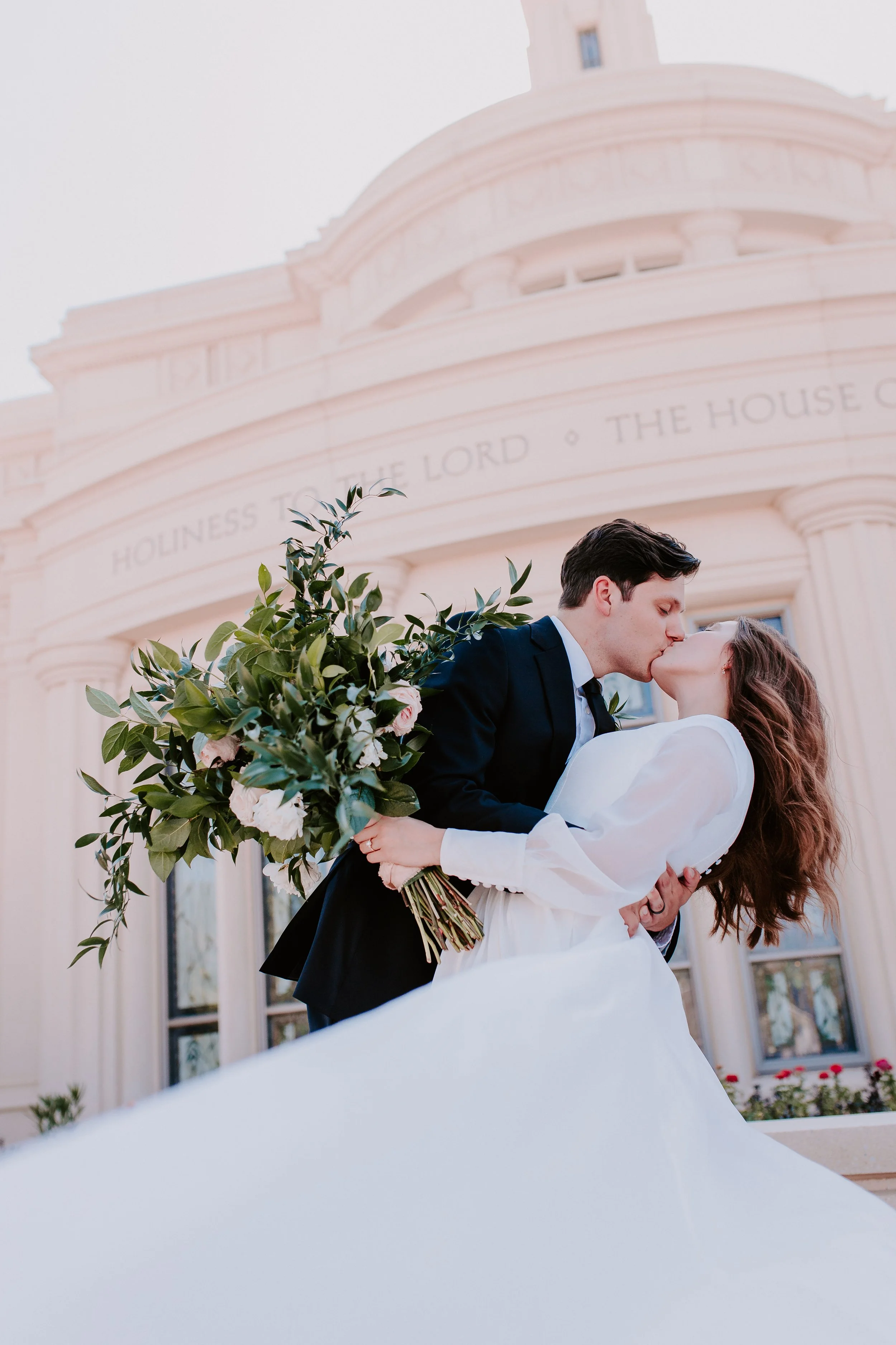 Bride and groom kissing in front of a temple