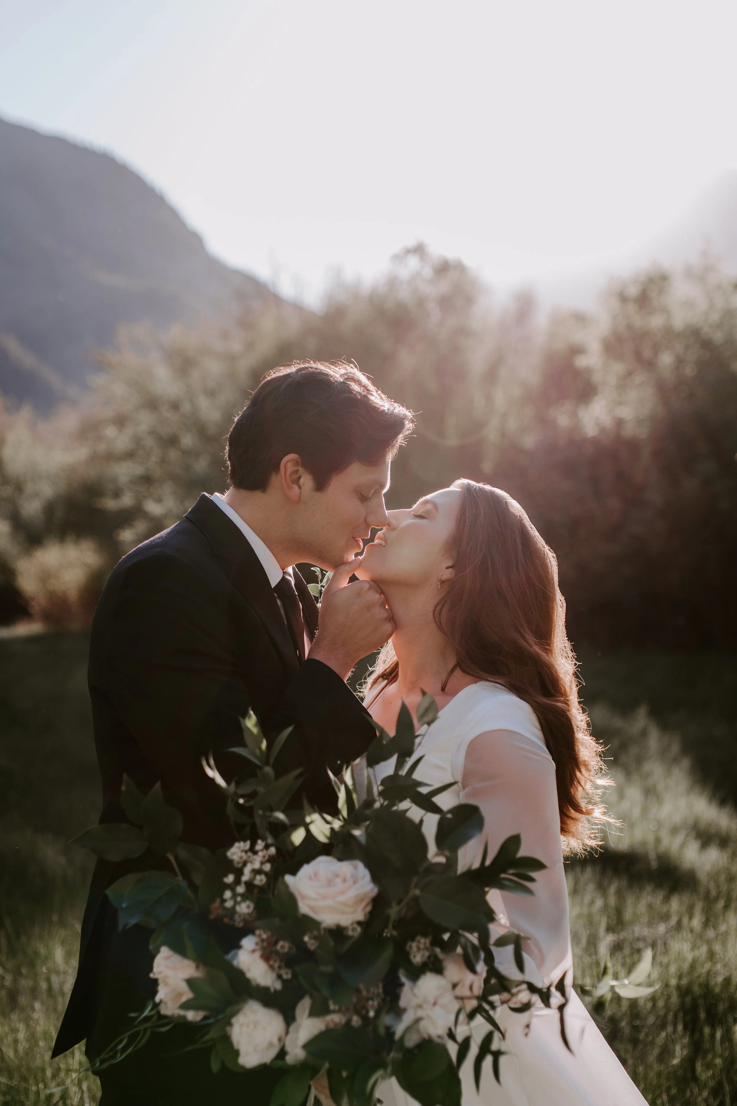 Bride and groom kissing at sunset