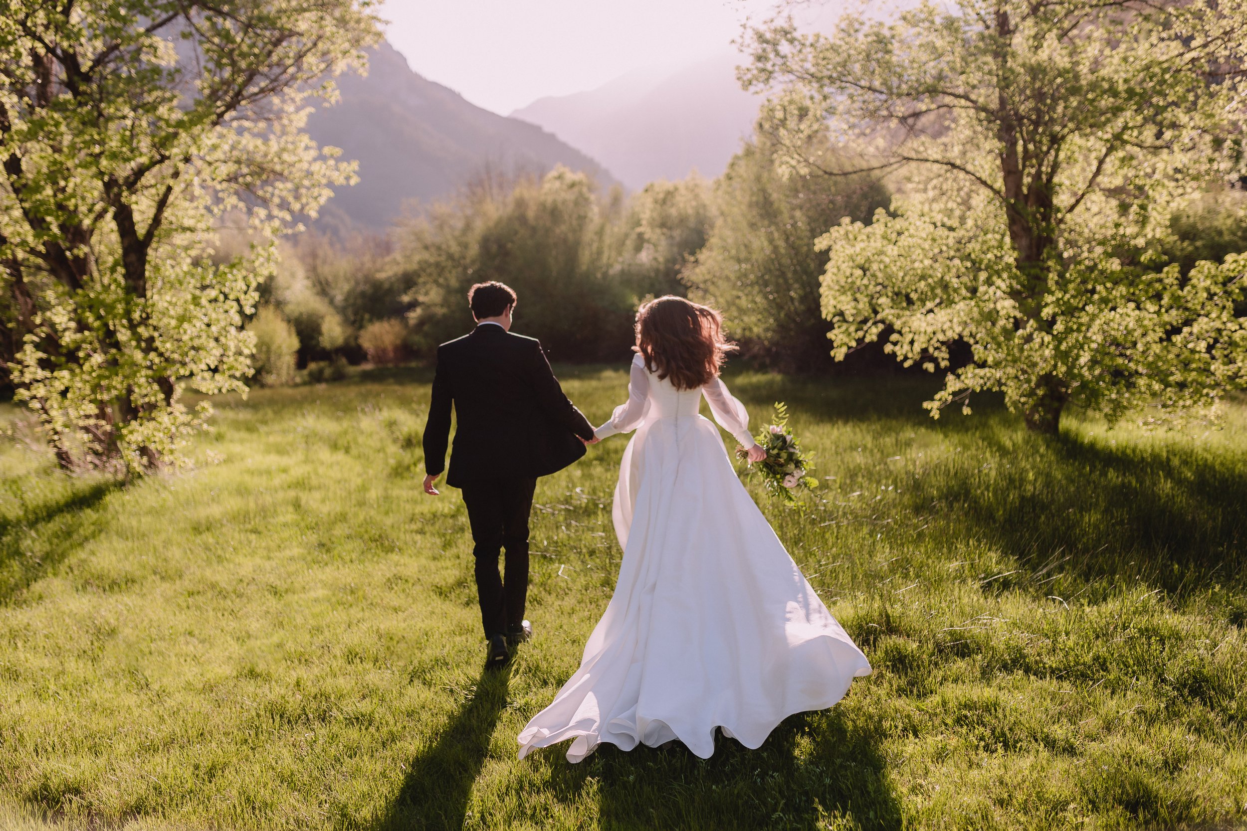 Bride and groom running in a field