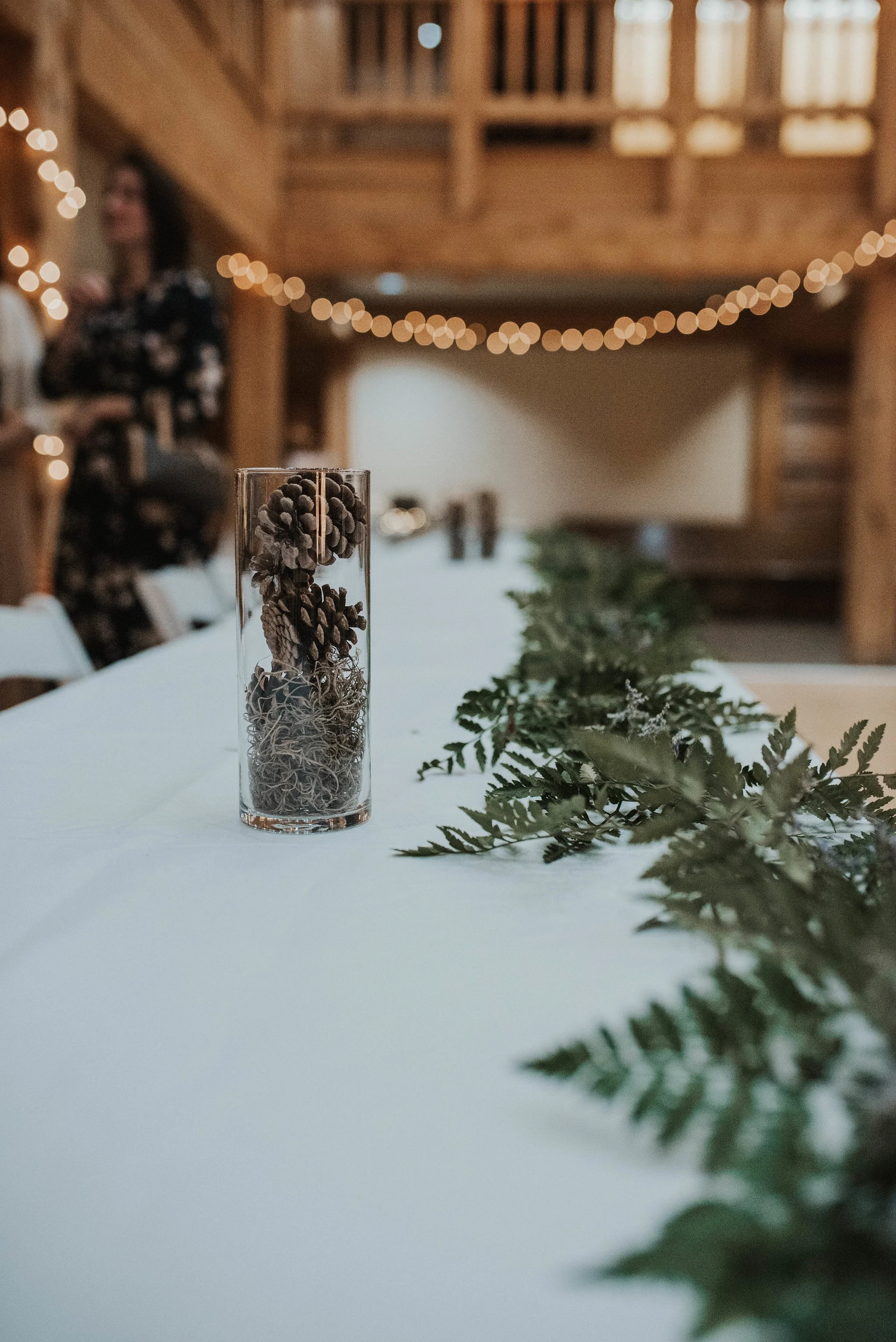 Table with greenery on it and vases full of pine cones