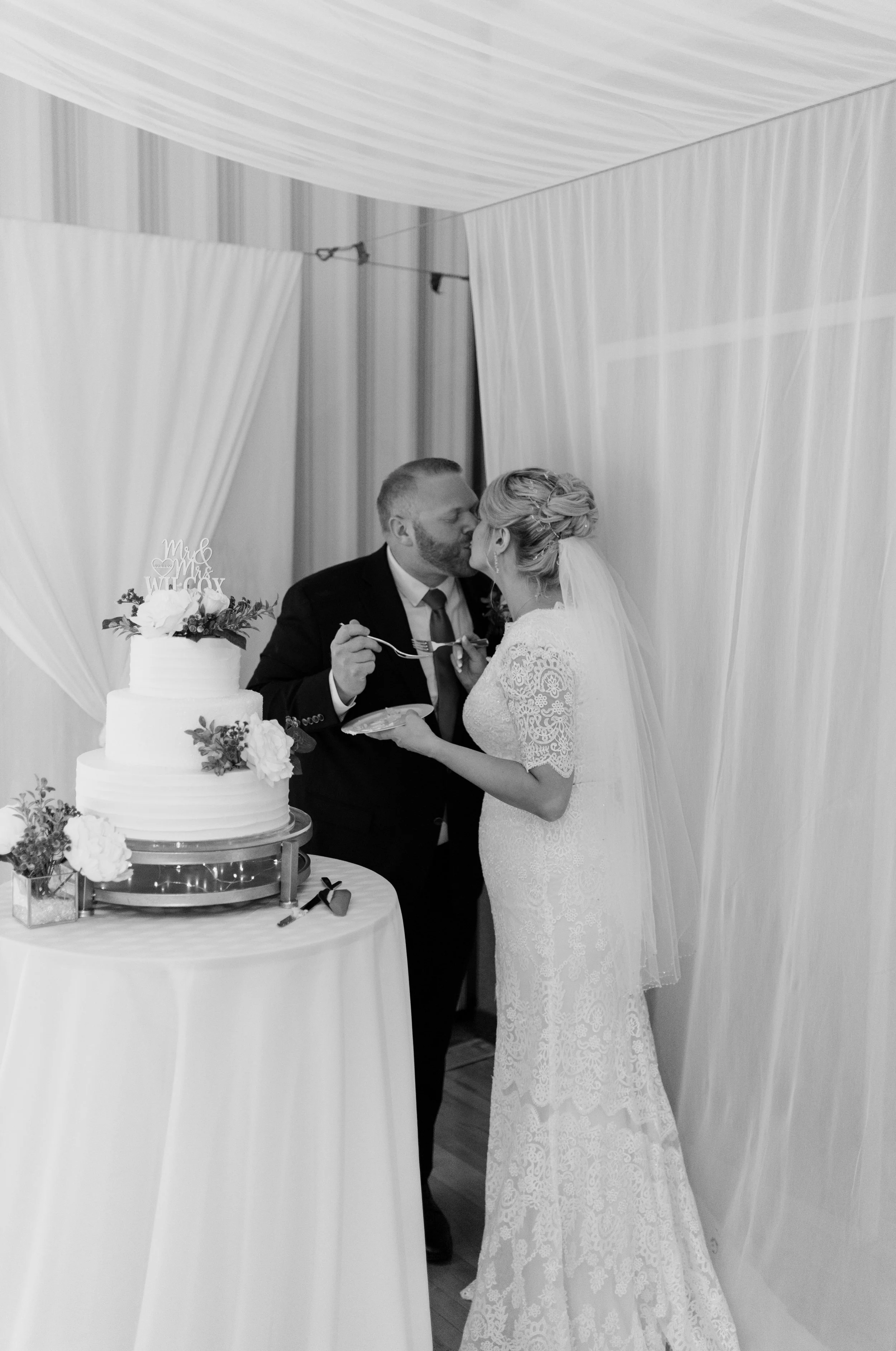 Bride and groom kissing in front of cake