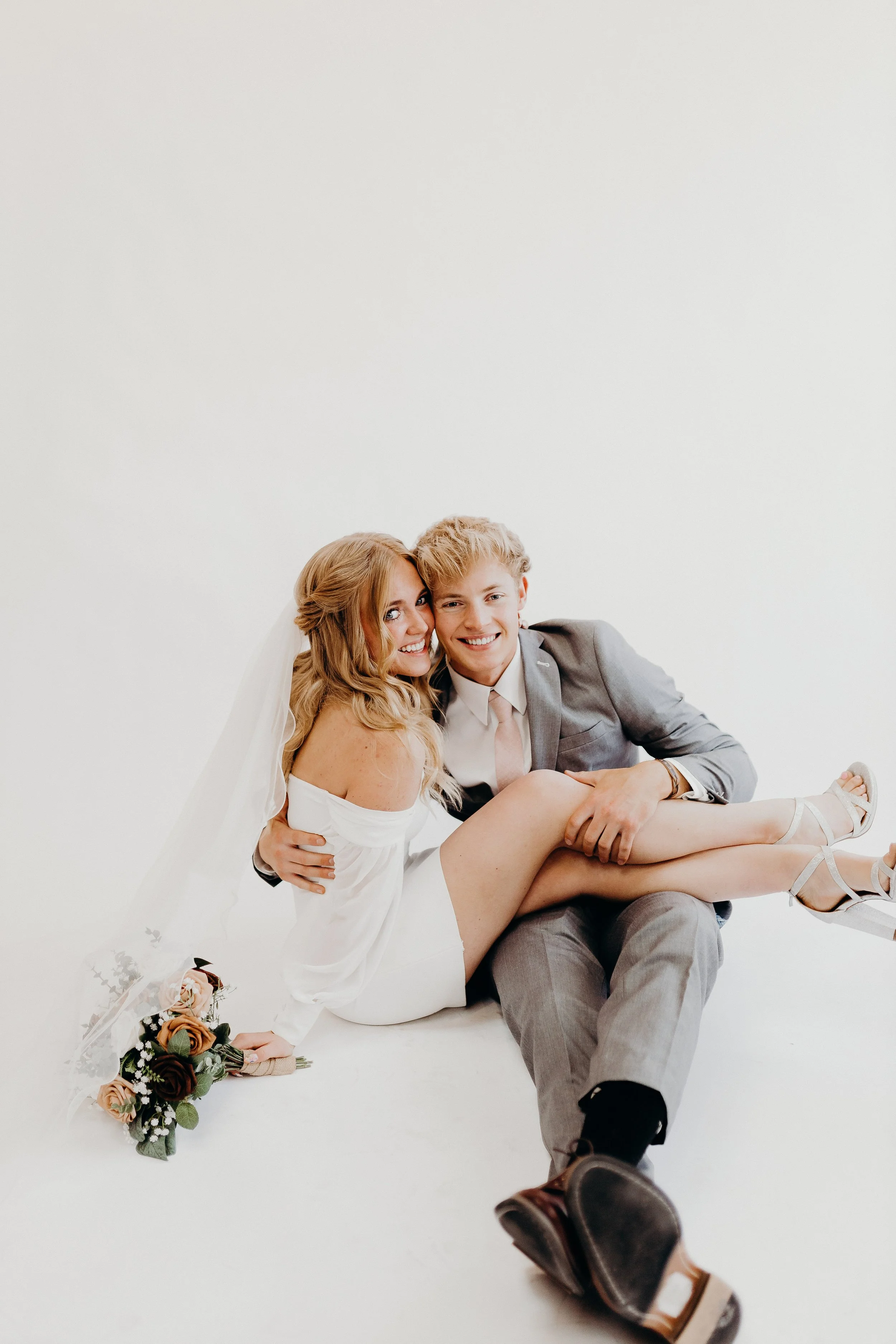 A bride sitting on the lap of her groom