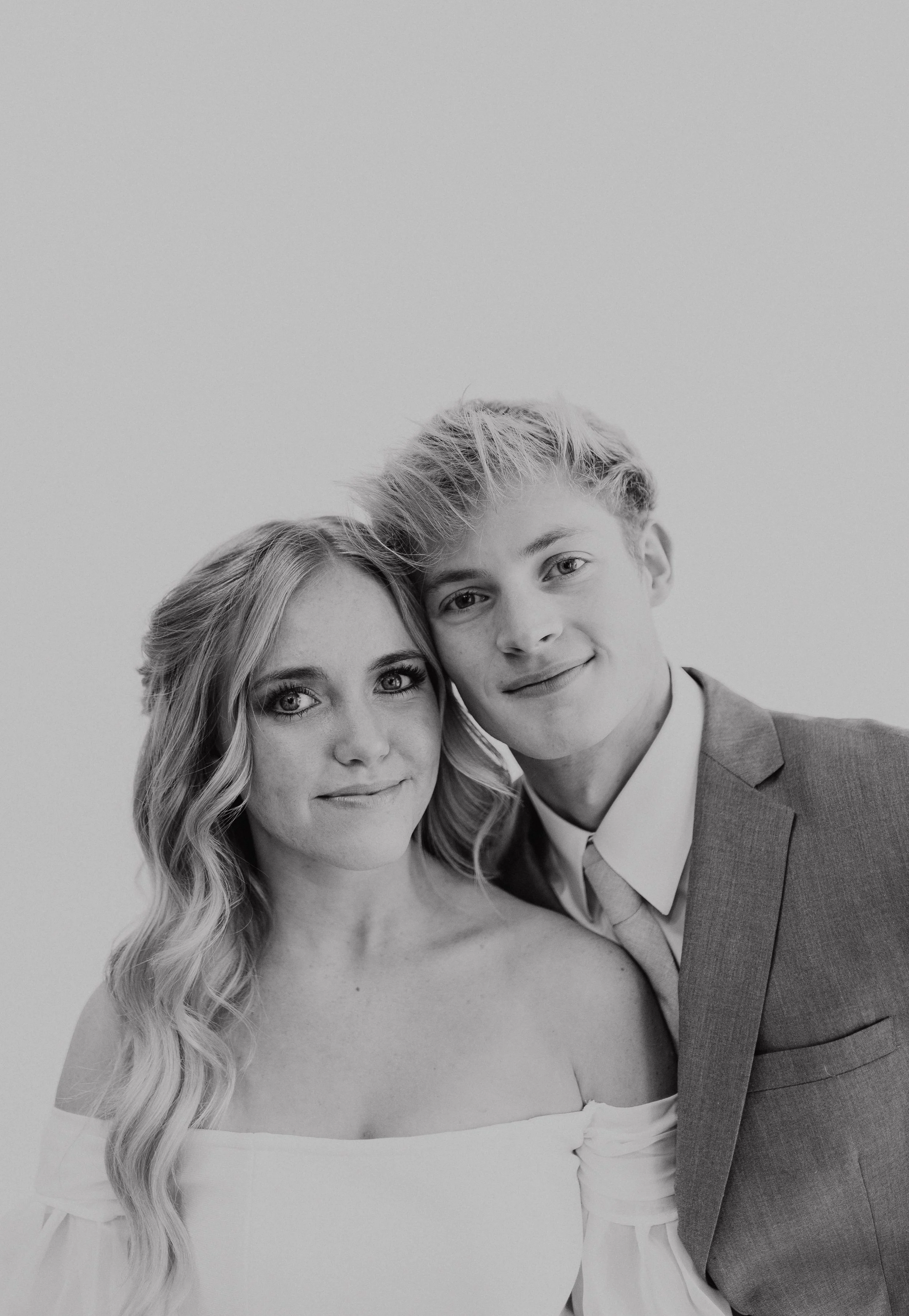A bride and groom standing face to face looking at the camera