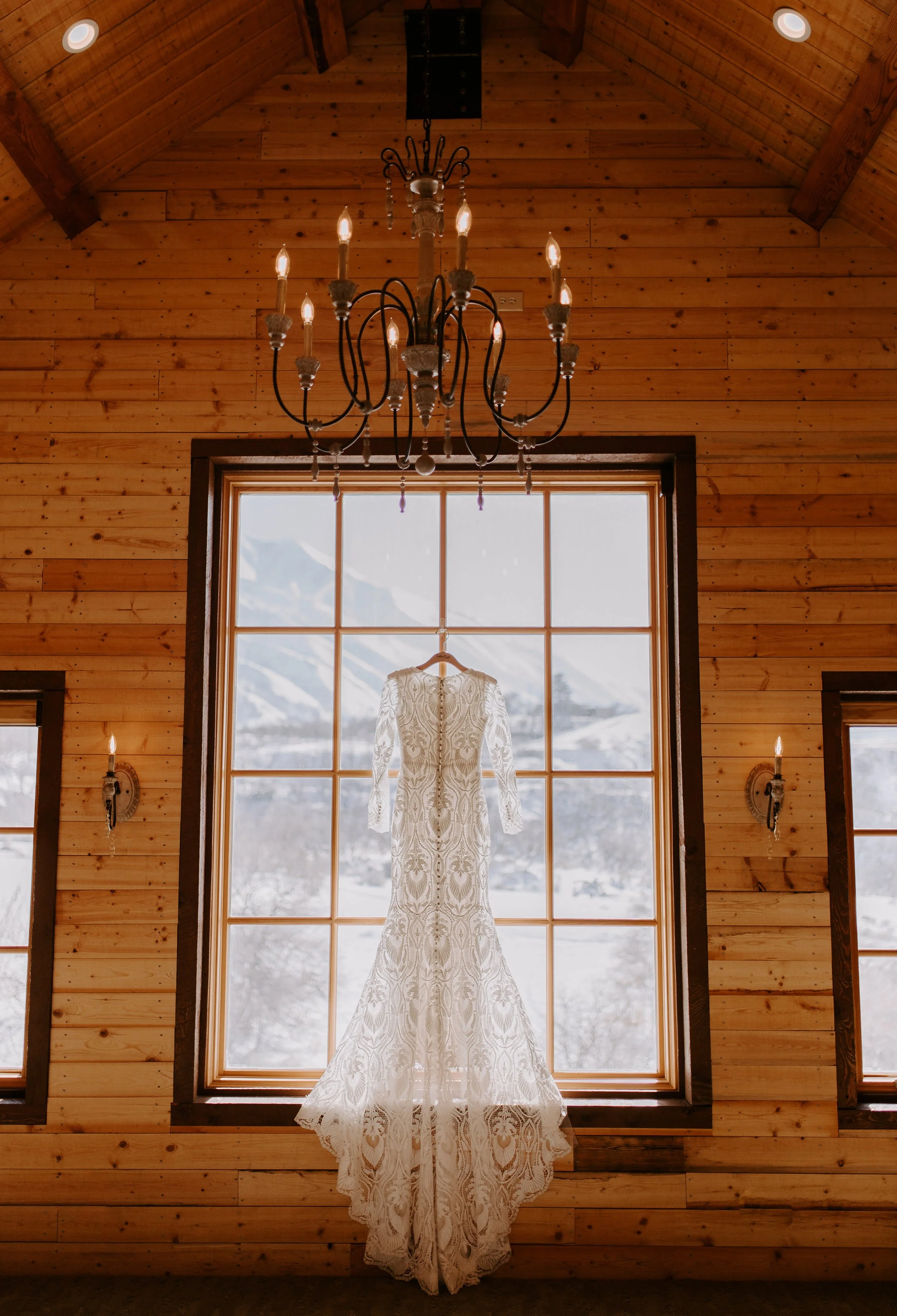 A wedding dress hanging up in front of a window