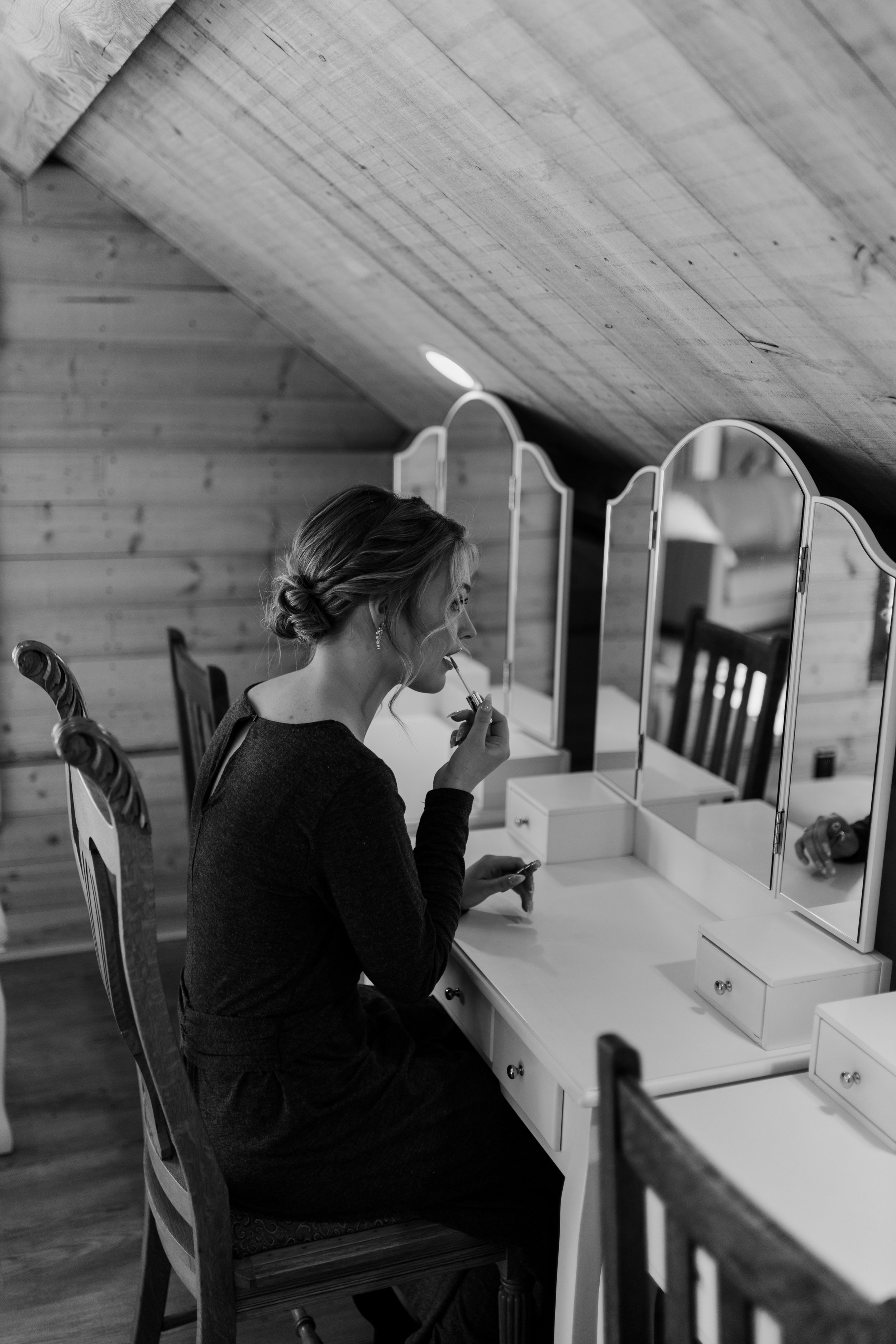 A woman applying makeup sitting down in front of a mirror