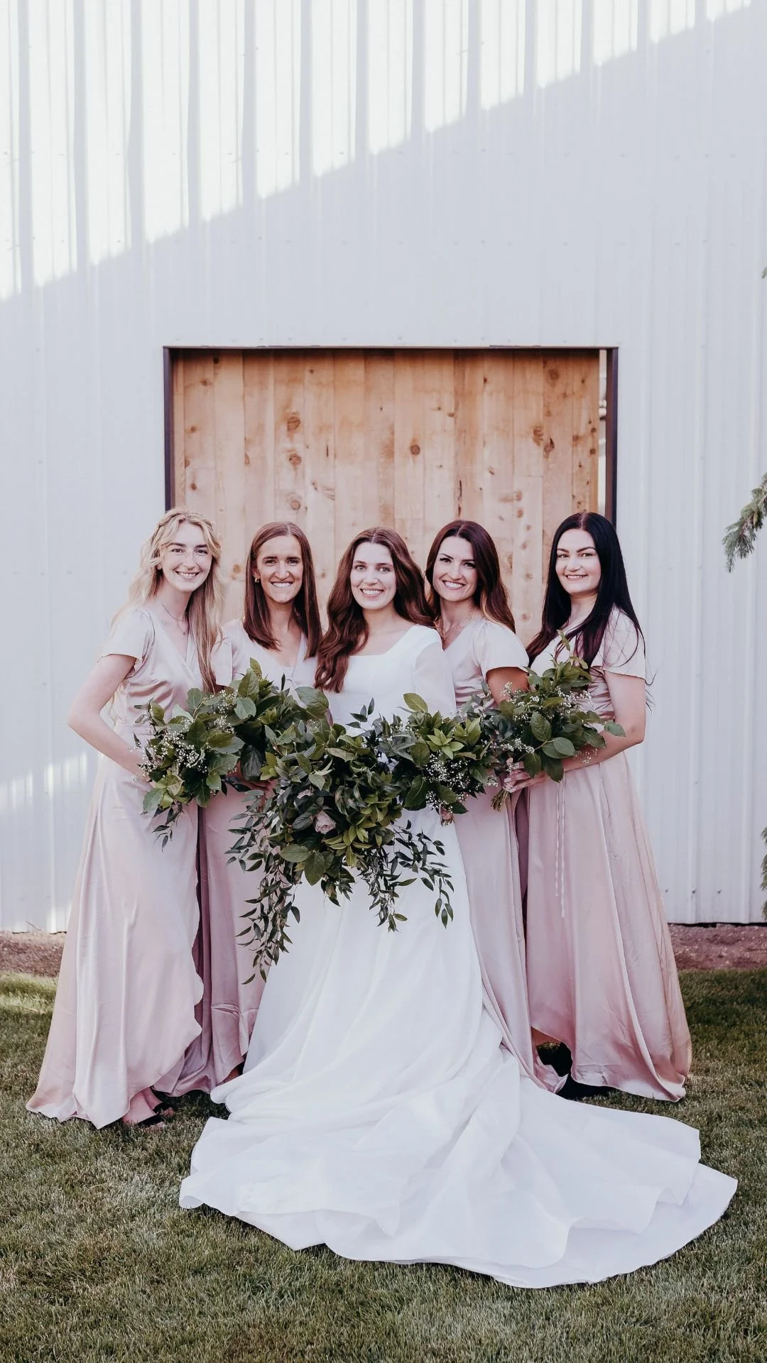 Bridesmaids in pink with the bride, holding green bouquets