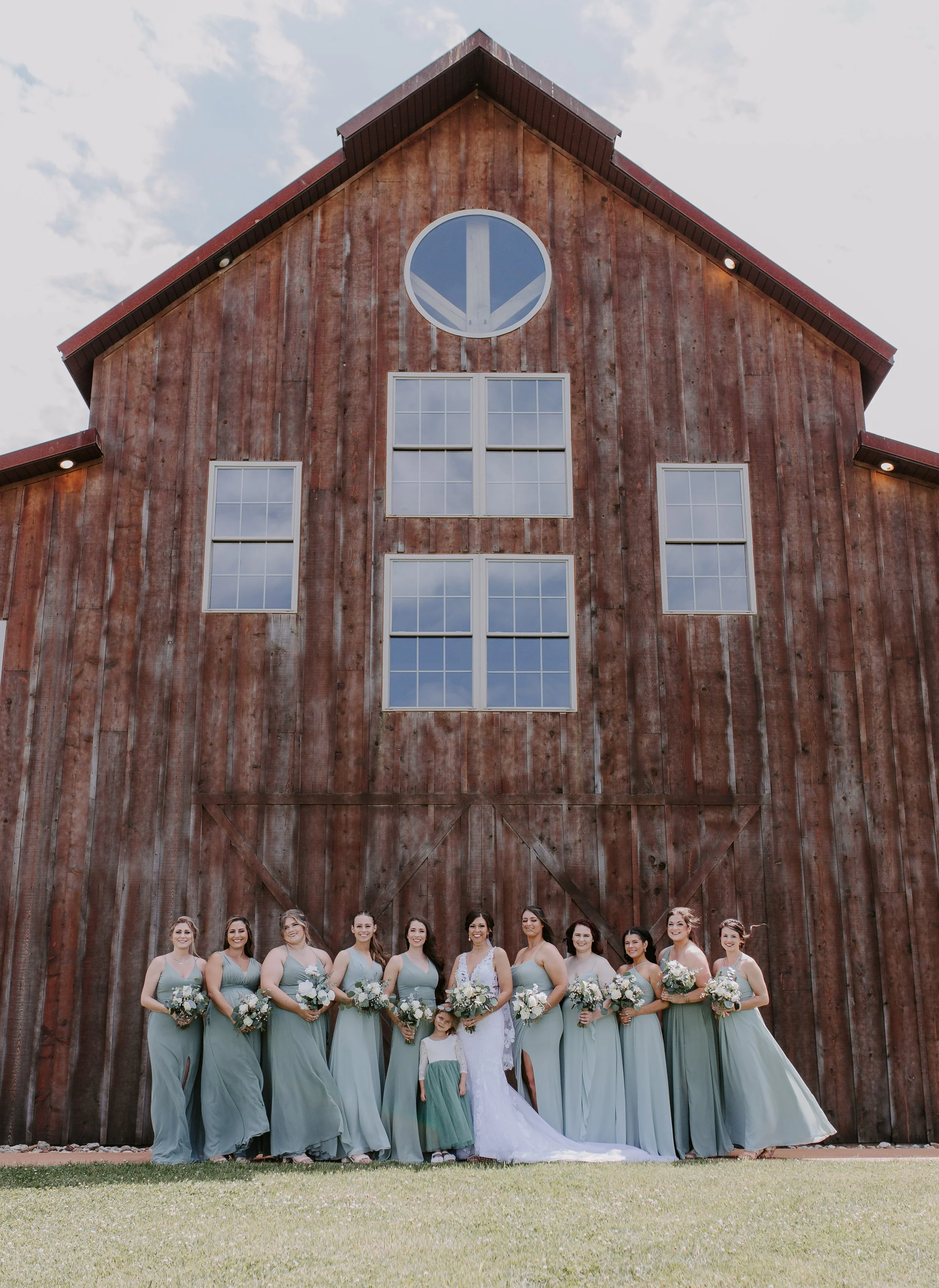 Bridesmaids and bride standing in front of barn 
