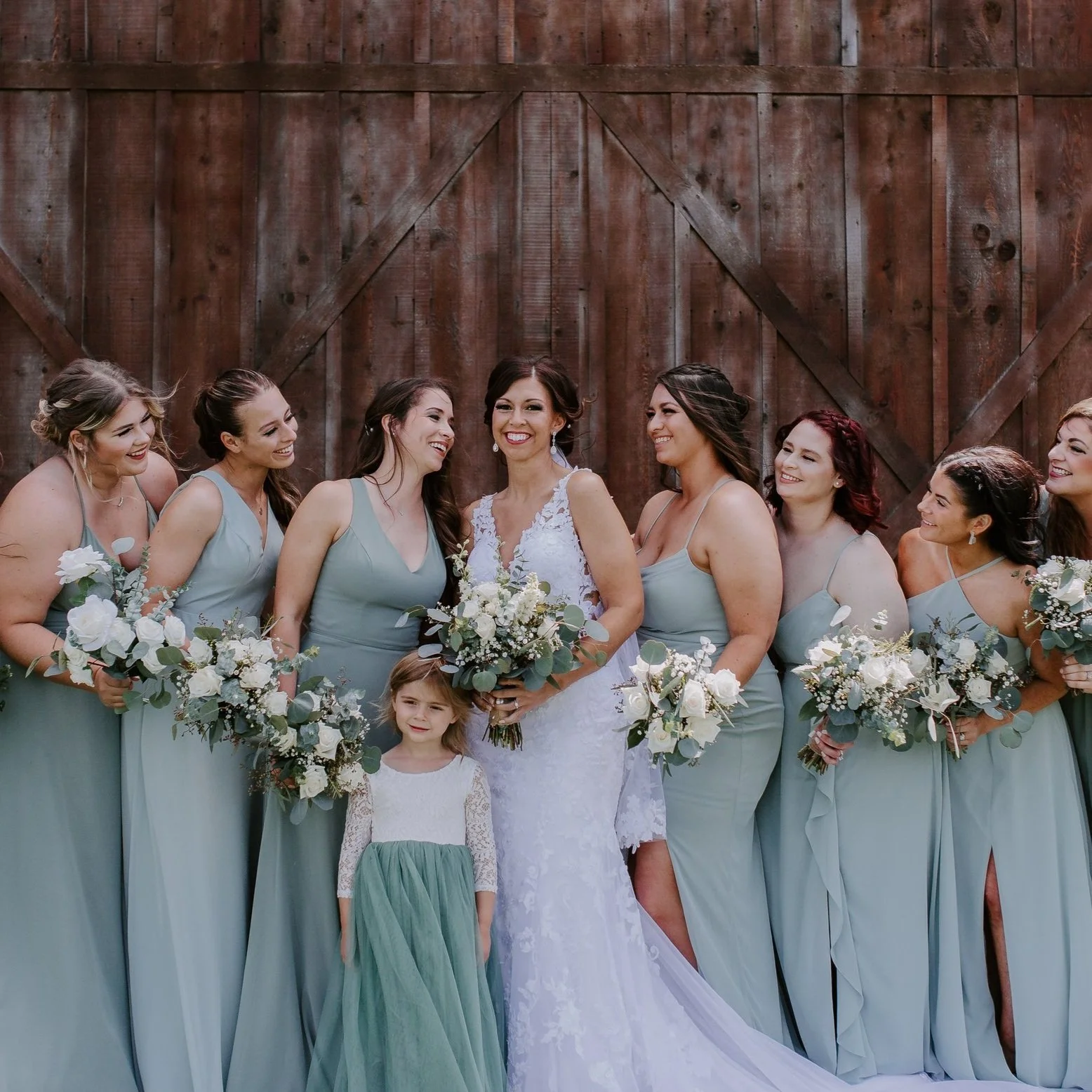 Bridesmaids standing in front of a barn with the bride and her daughter