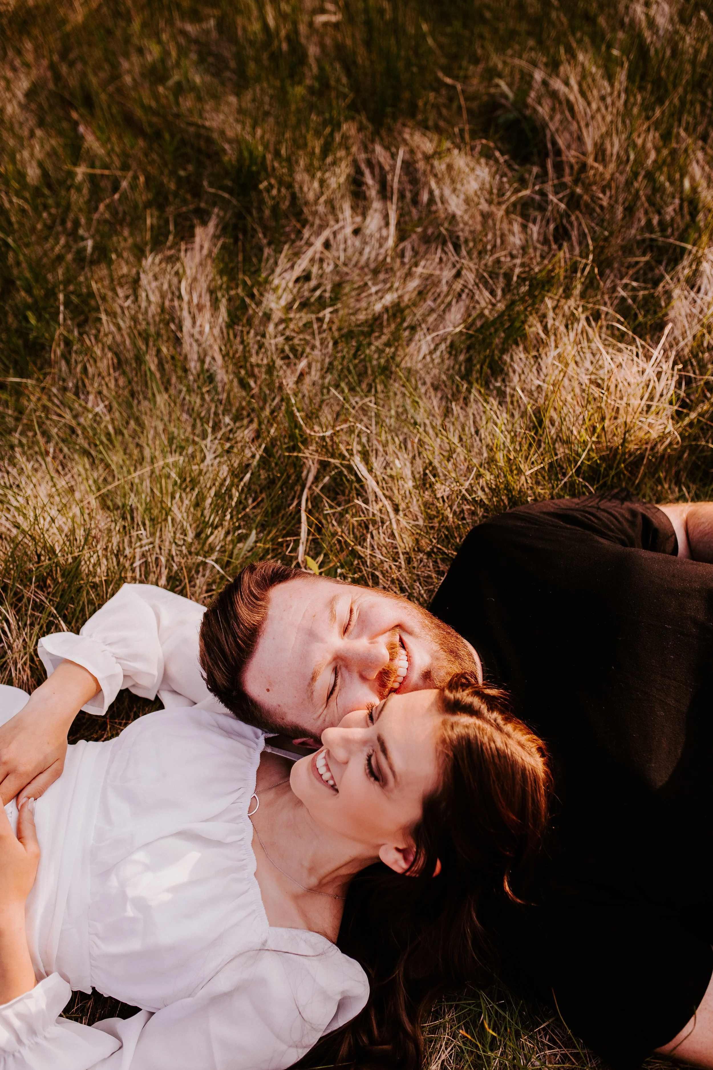 Couple laying in grass during golden hour