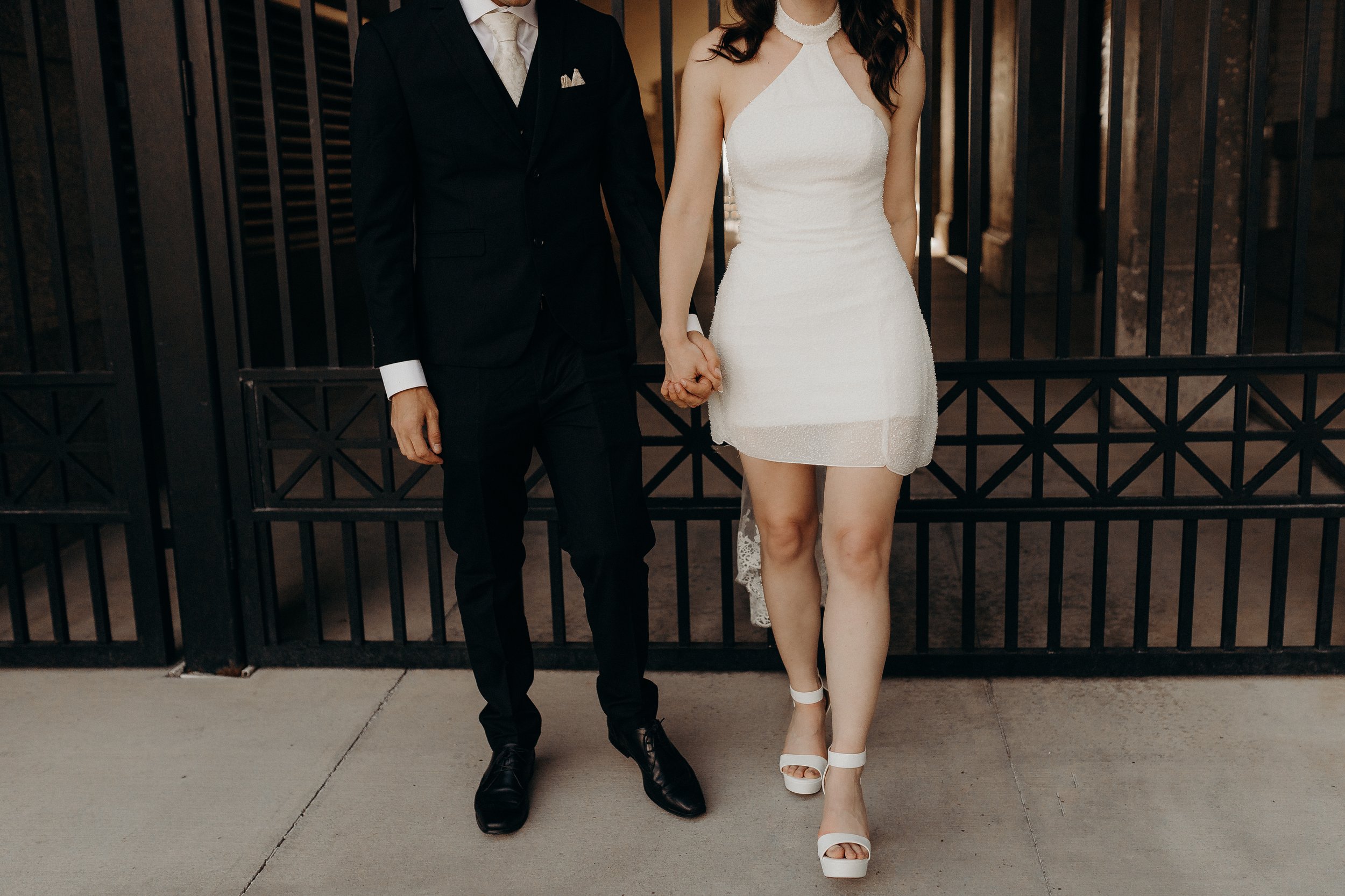 Bridal couple in vintage wedding outfits in front of black gate