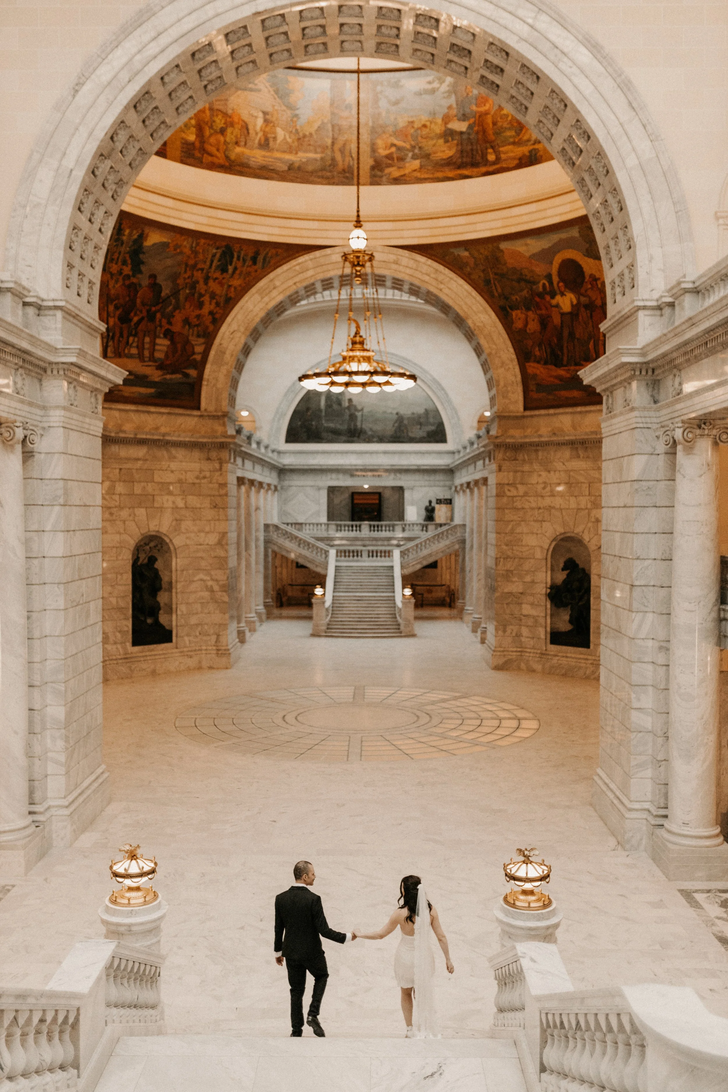 Couple walking down Utah State Capitol steps in main area of building