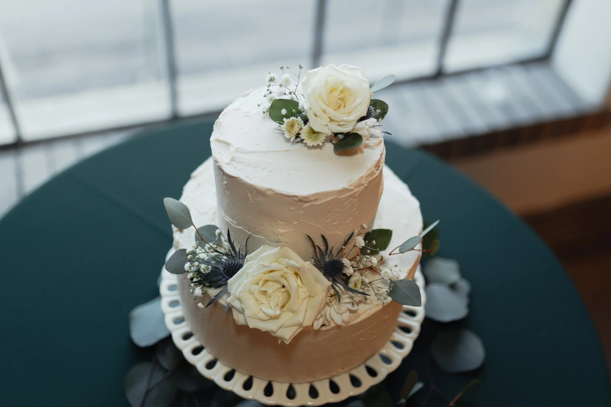White wedding cake with flowers on it over a green tablecloth