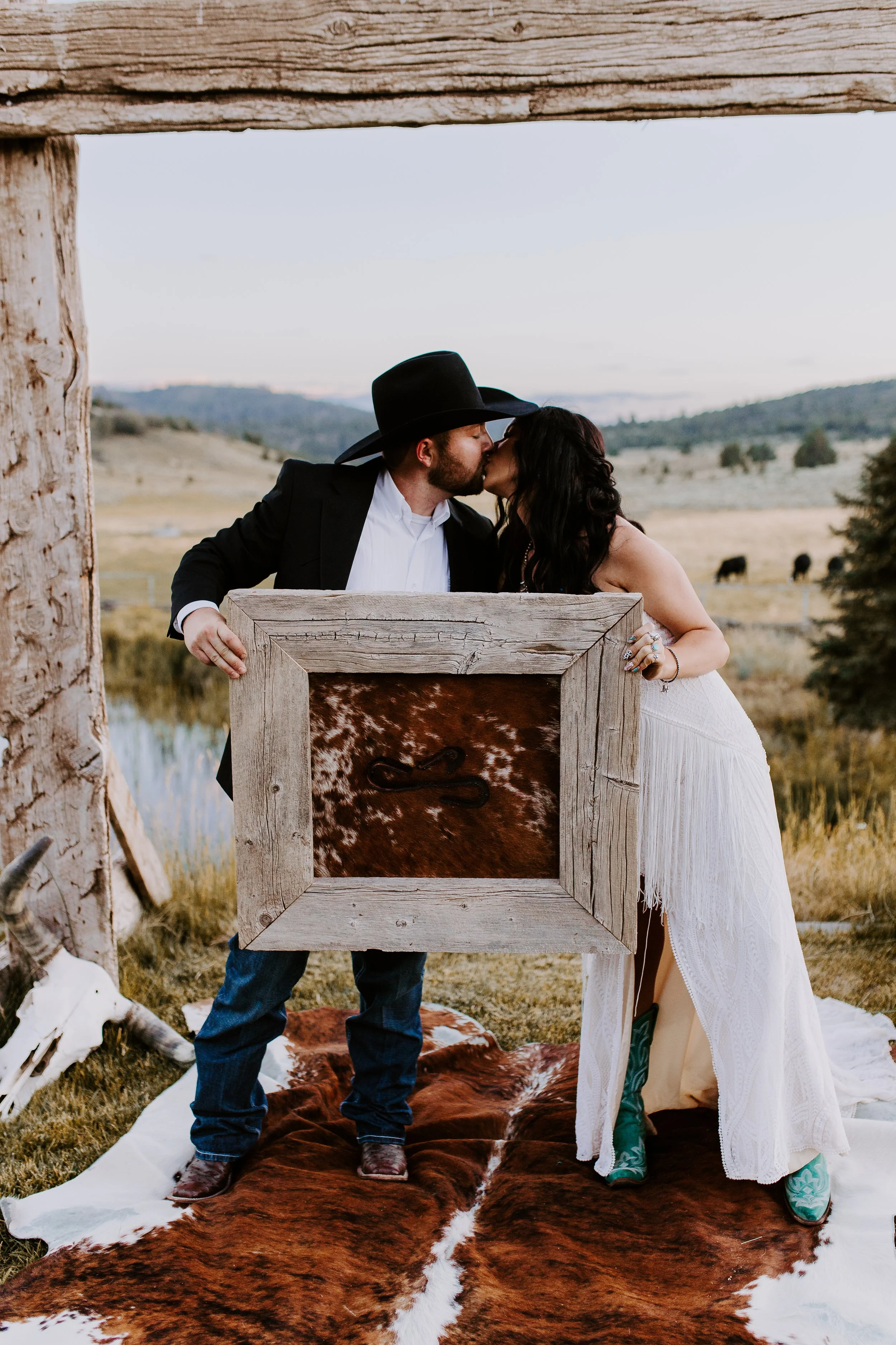 Bride and groom holding up a hide that they branded on wedding day