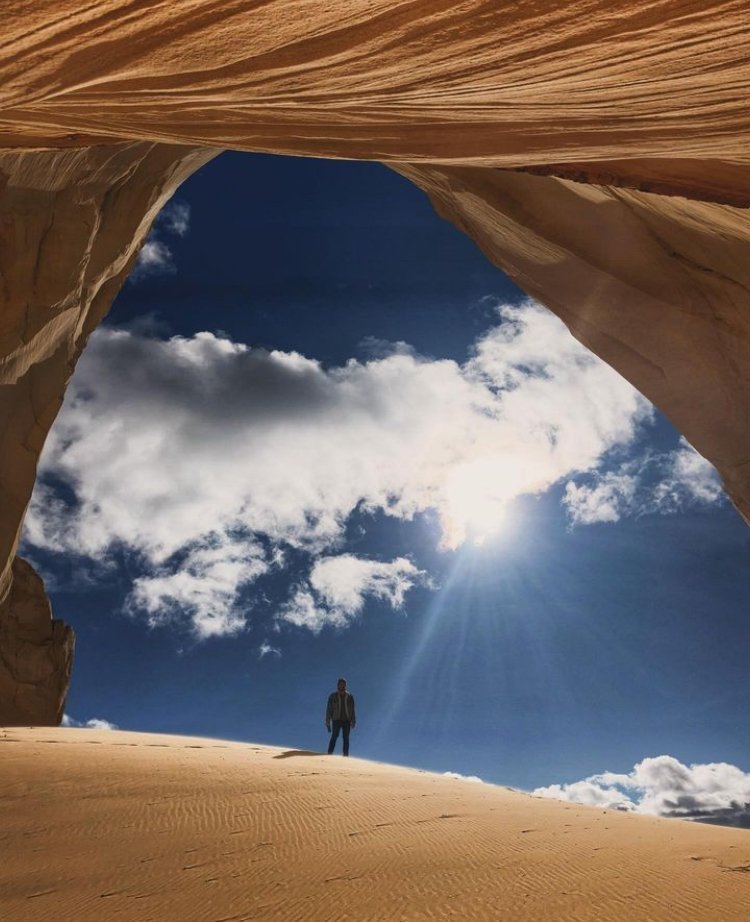A person standing on a sand dune inside a cave