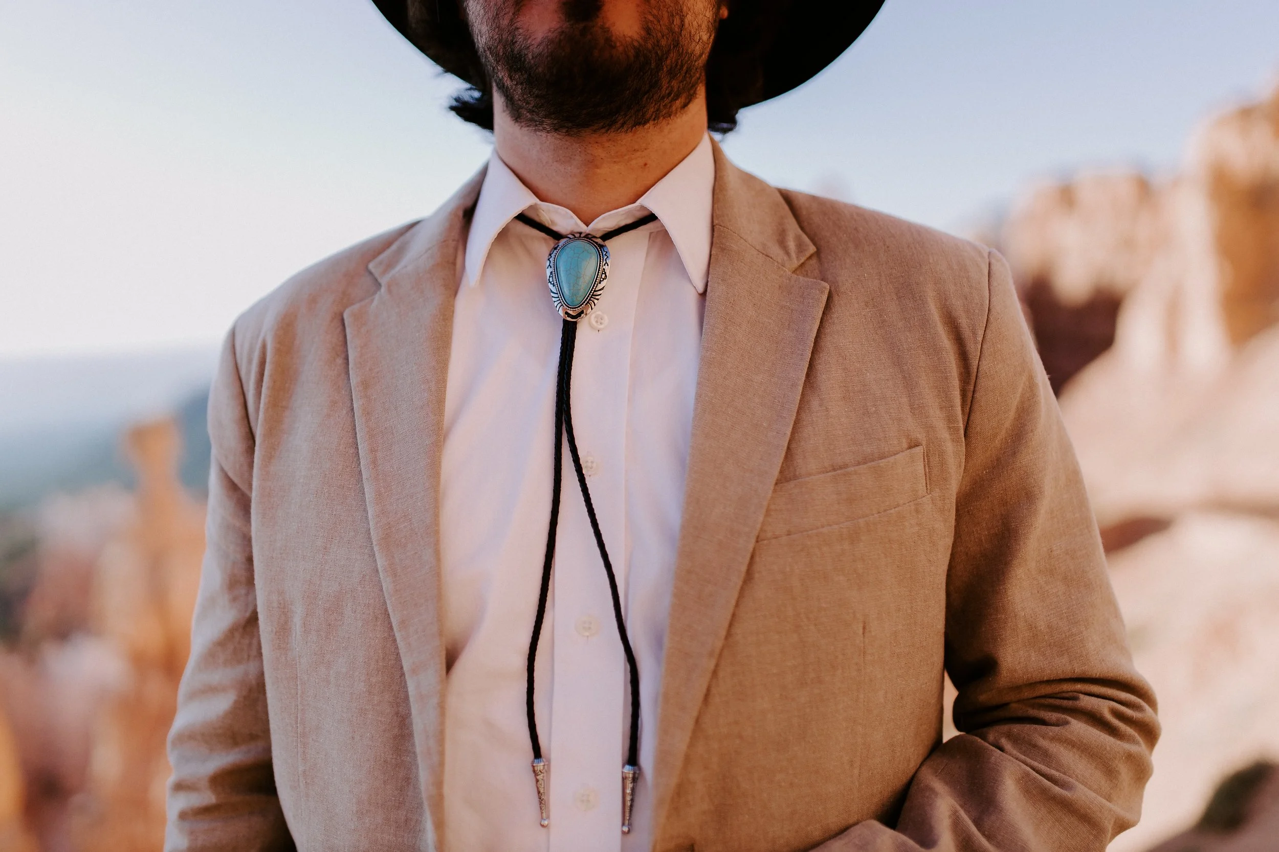 A man in a tan suit with a bolo tie