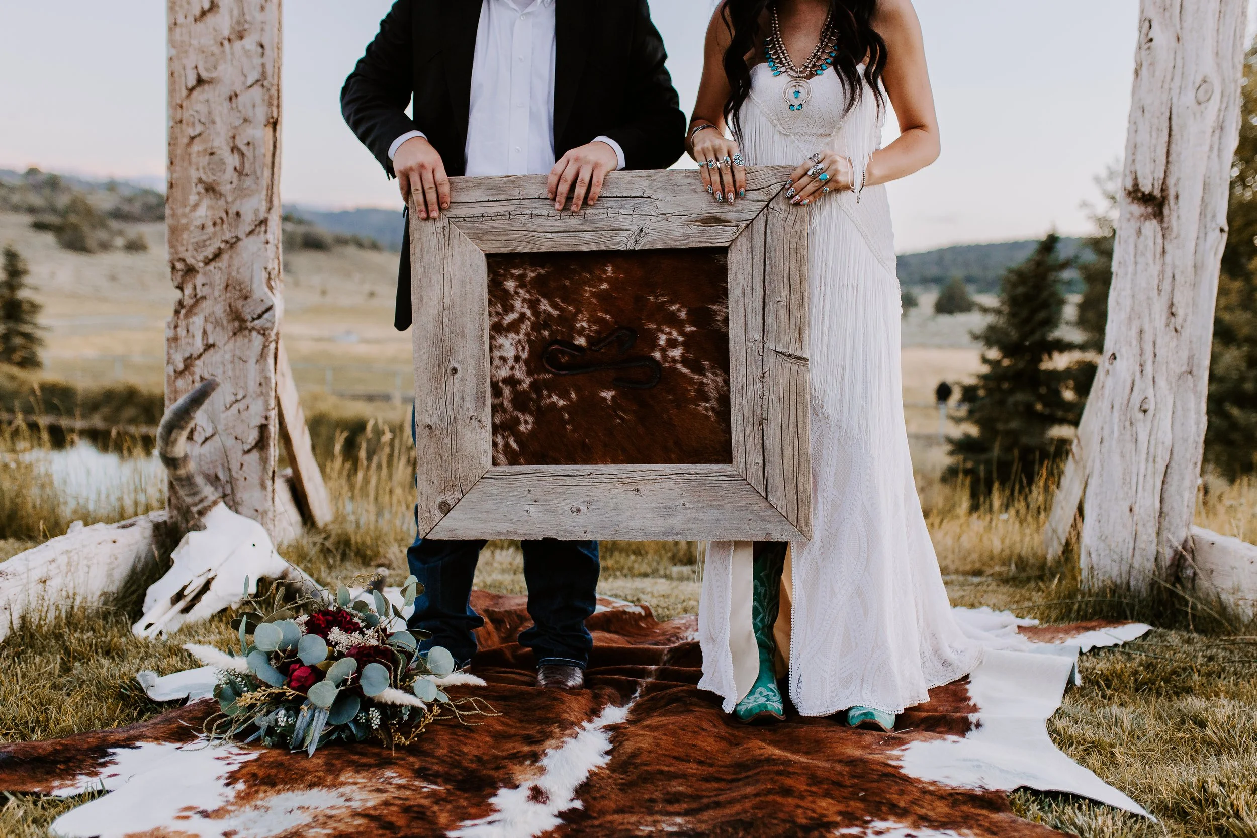 A bride and groom holding up a wooden frame