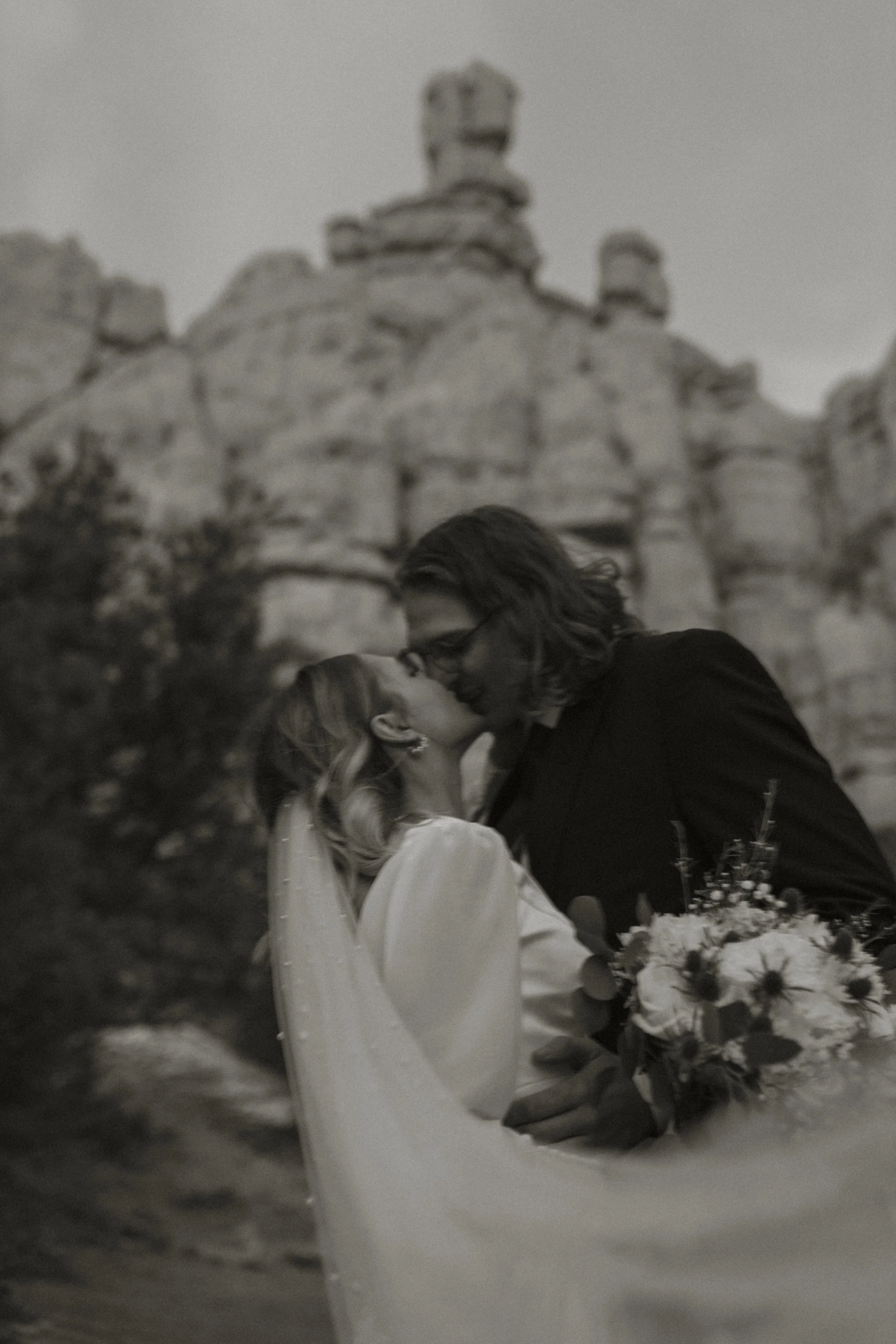A bride and groom kissing with red rock in the background