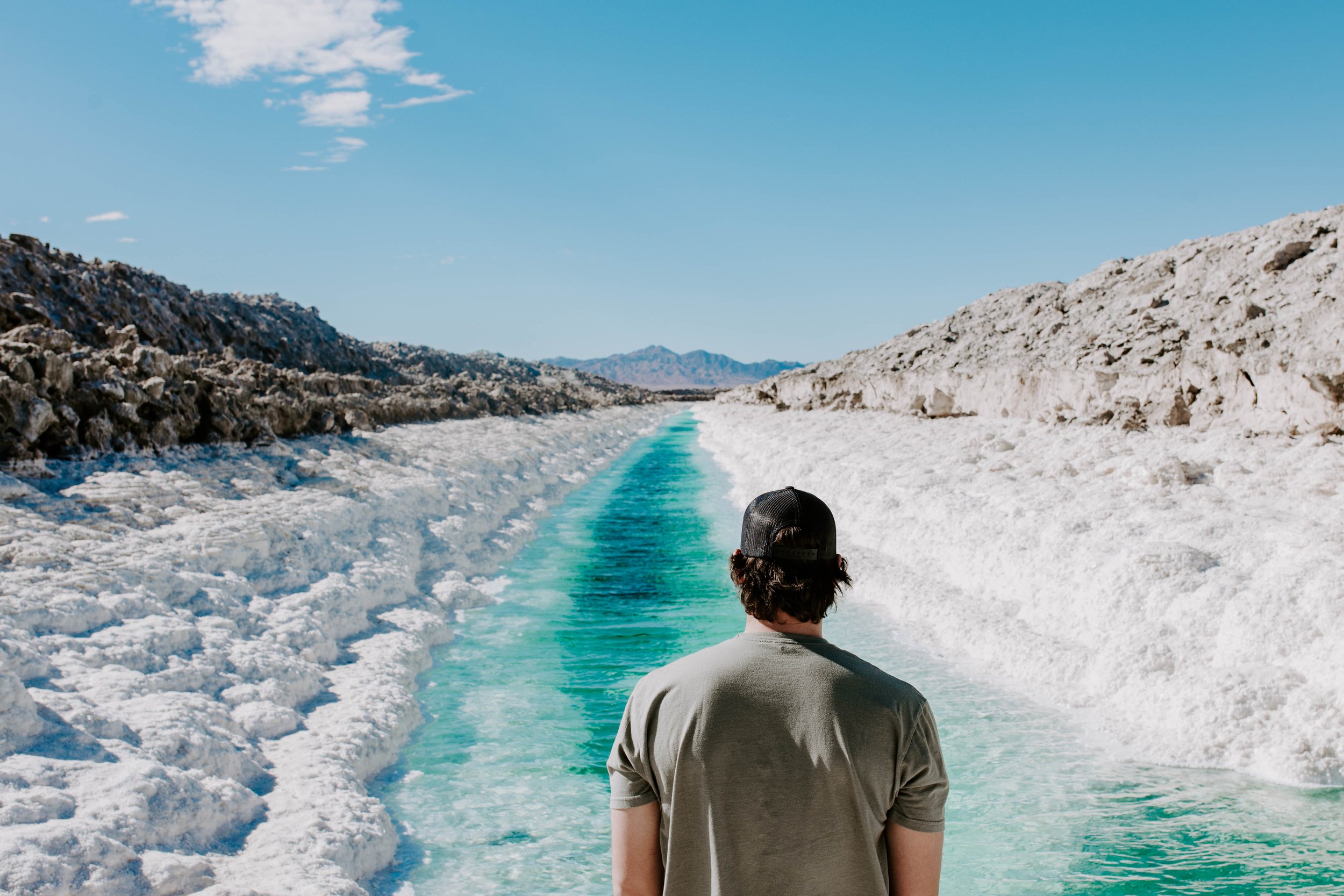 Man looking at teal river surround by salt