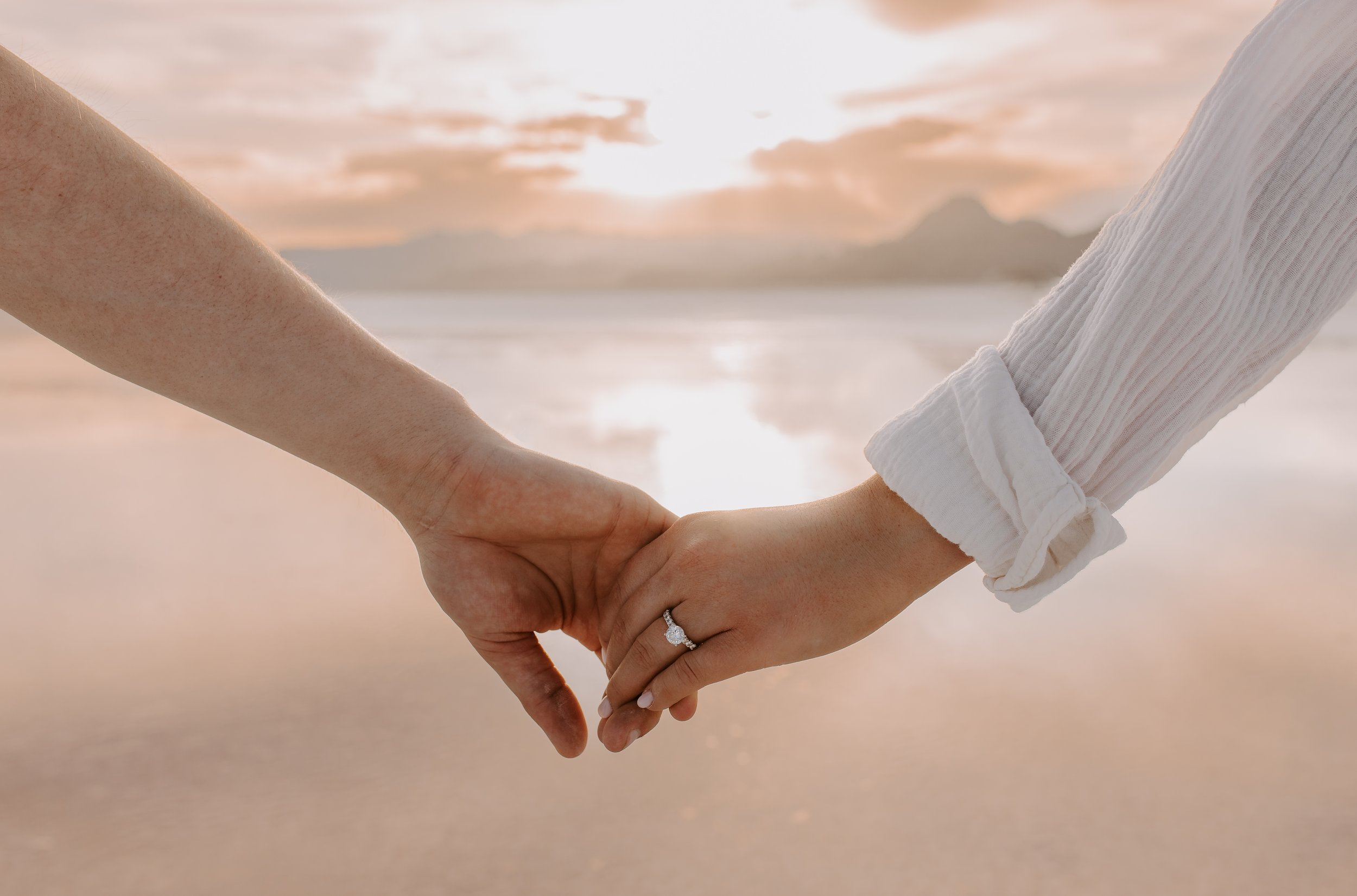 Couple holding hands on salt flats with mountains in the background