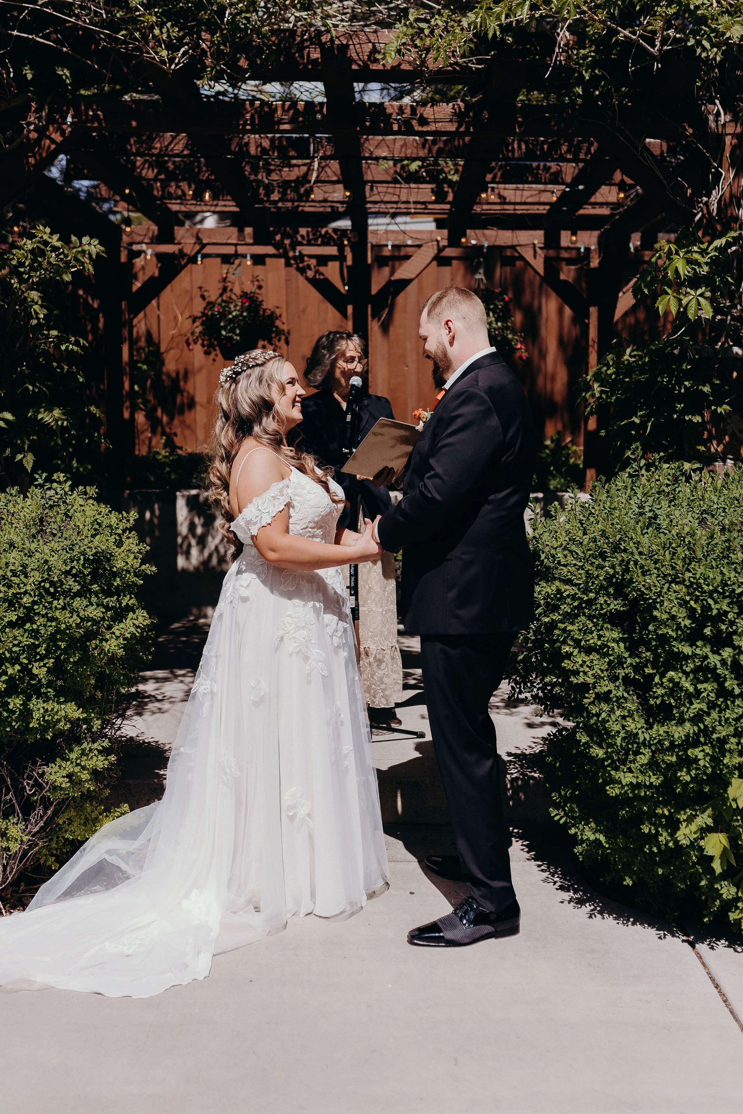 Bride and groom at ceremony in front of wooden pergola background 