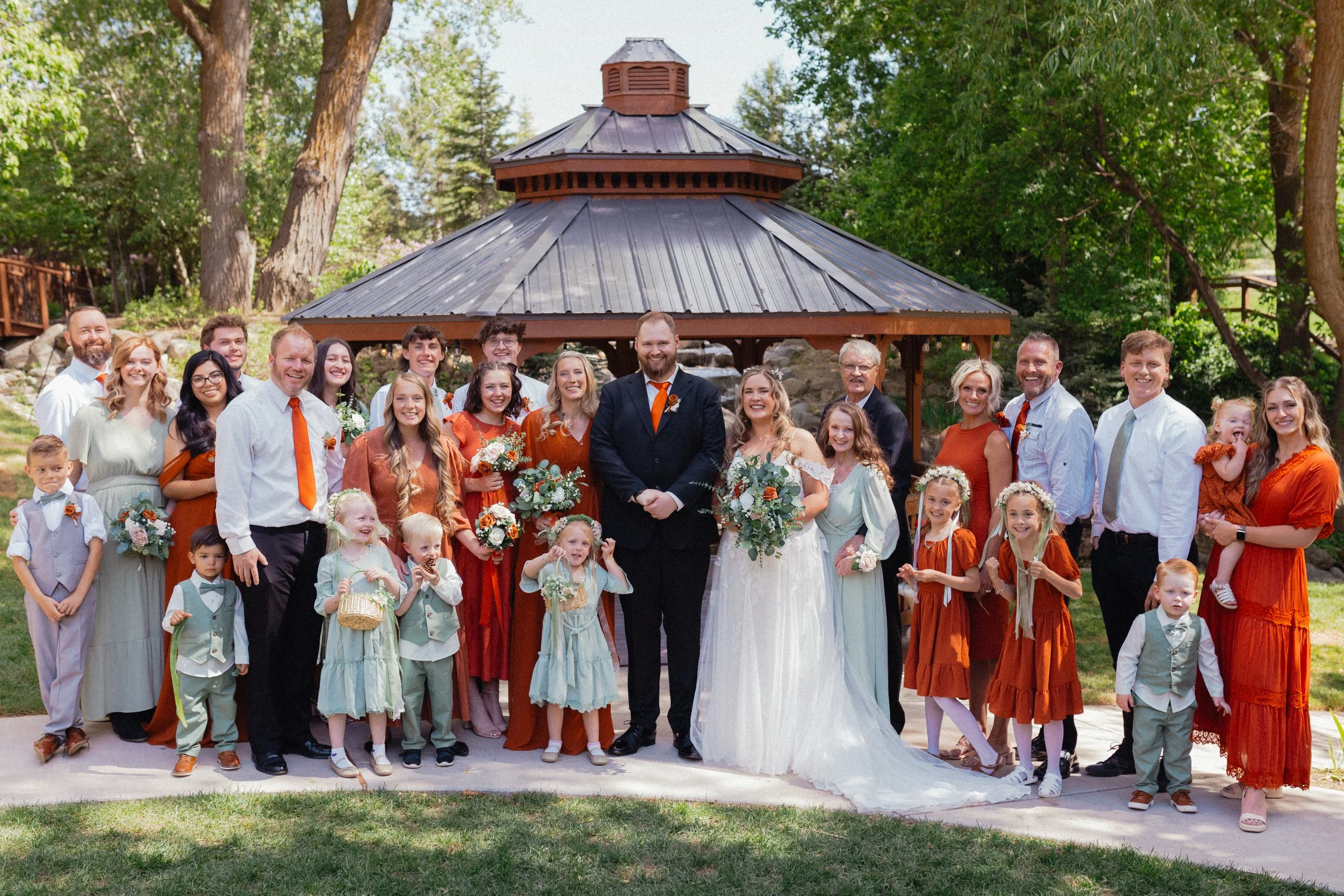 Bride and groom smiling with family dressed in orange and green colors