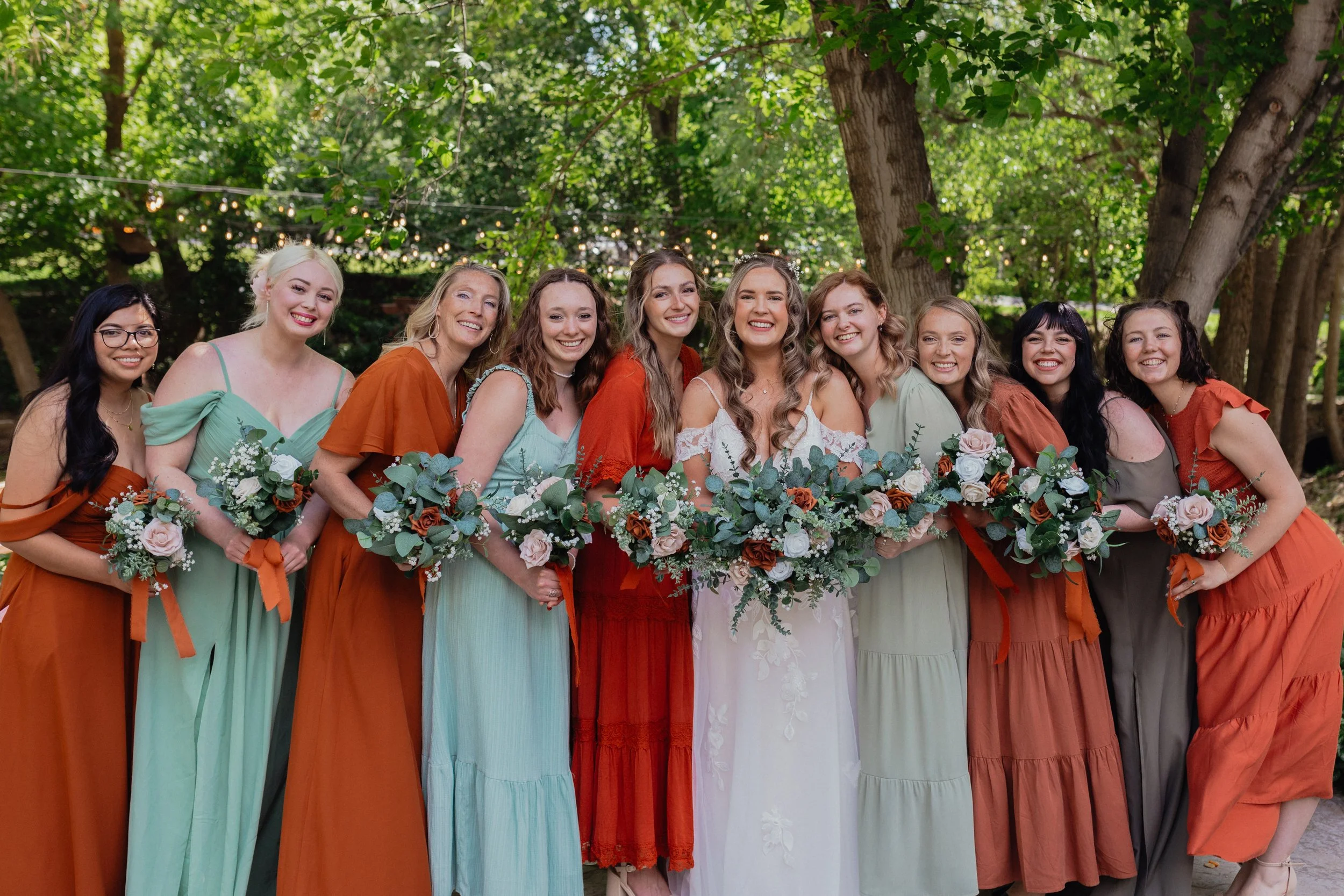 Bride surrounded by bridesmaids in orange and green dresses
