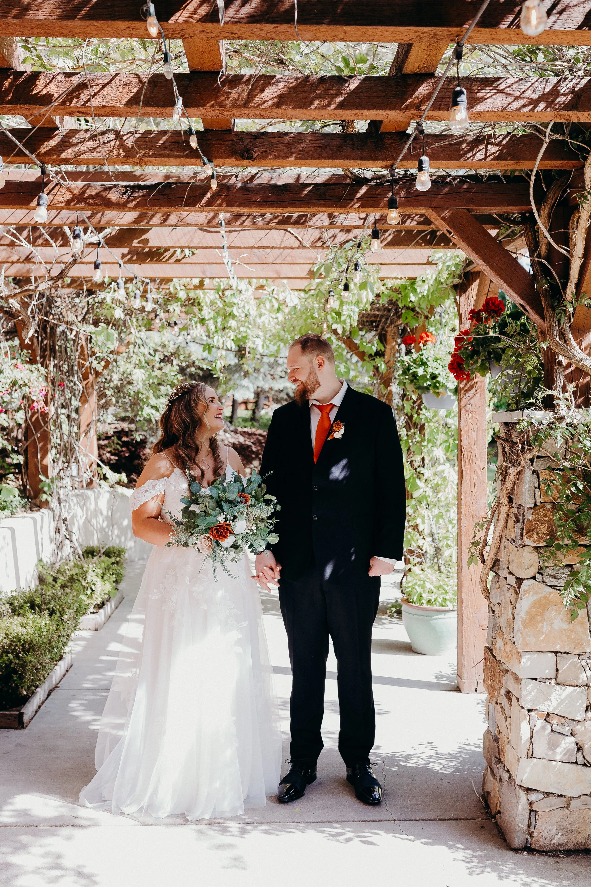 Bride and groom walking under pergola with vines hanging on it
