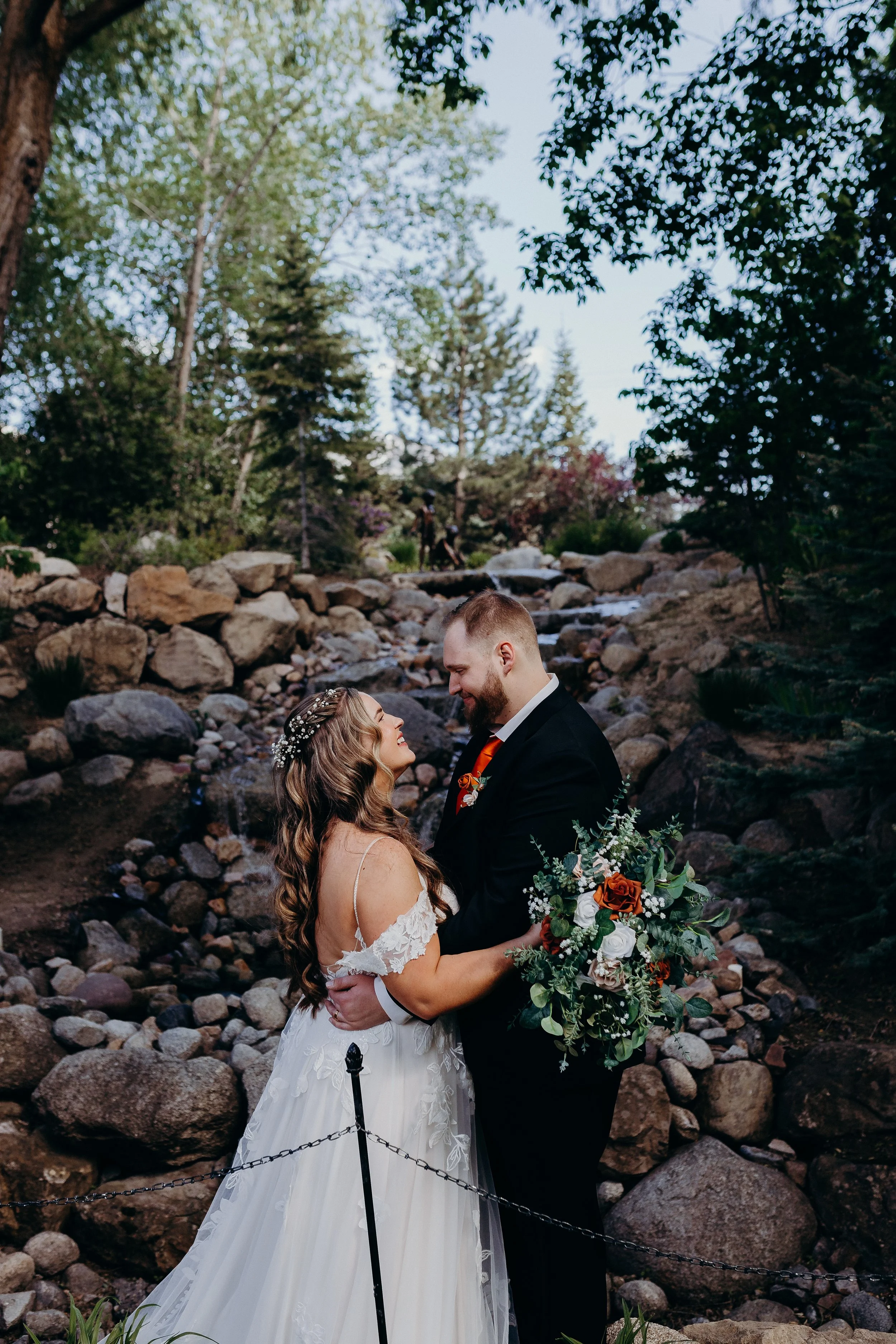 Bride and groom looking at each other in front of waterfall