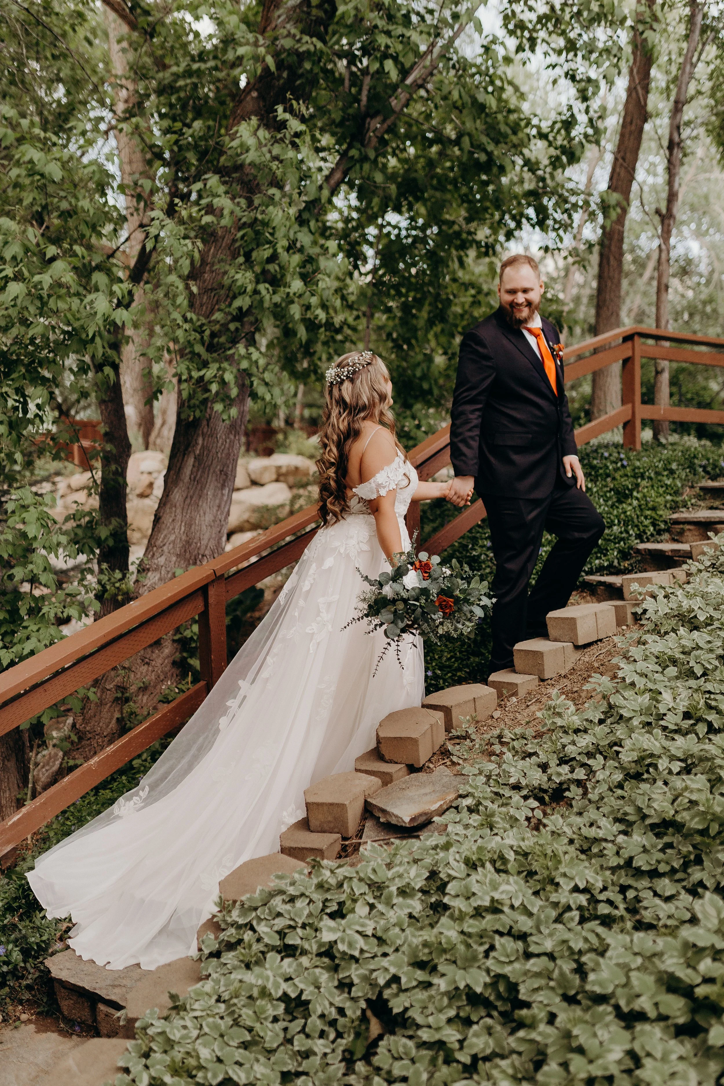 Bride and groom walking up staircase surrounded by greenery