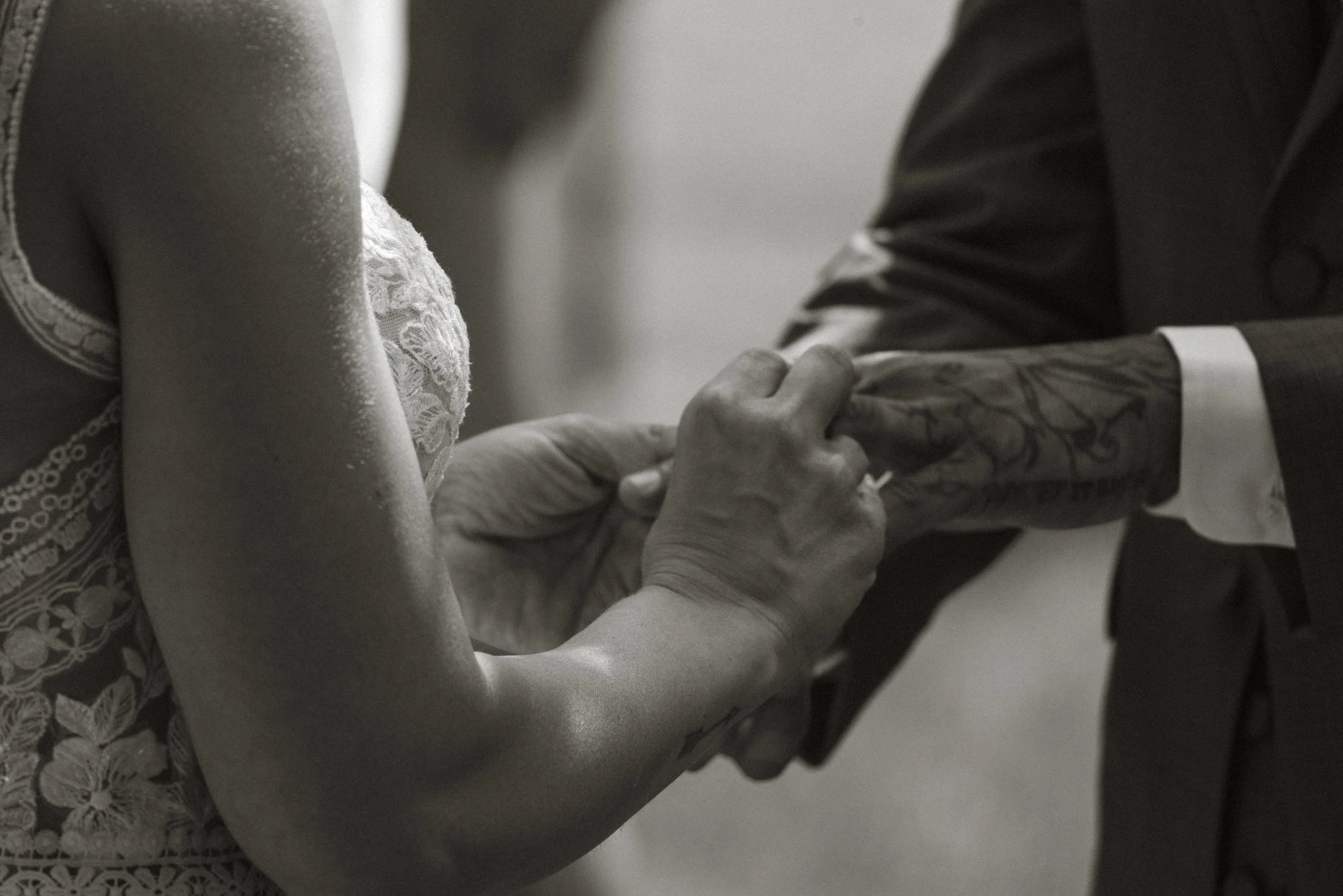 Bride putting ring on groom's hand up close