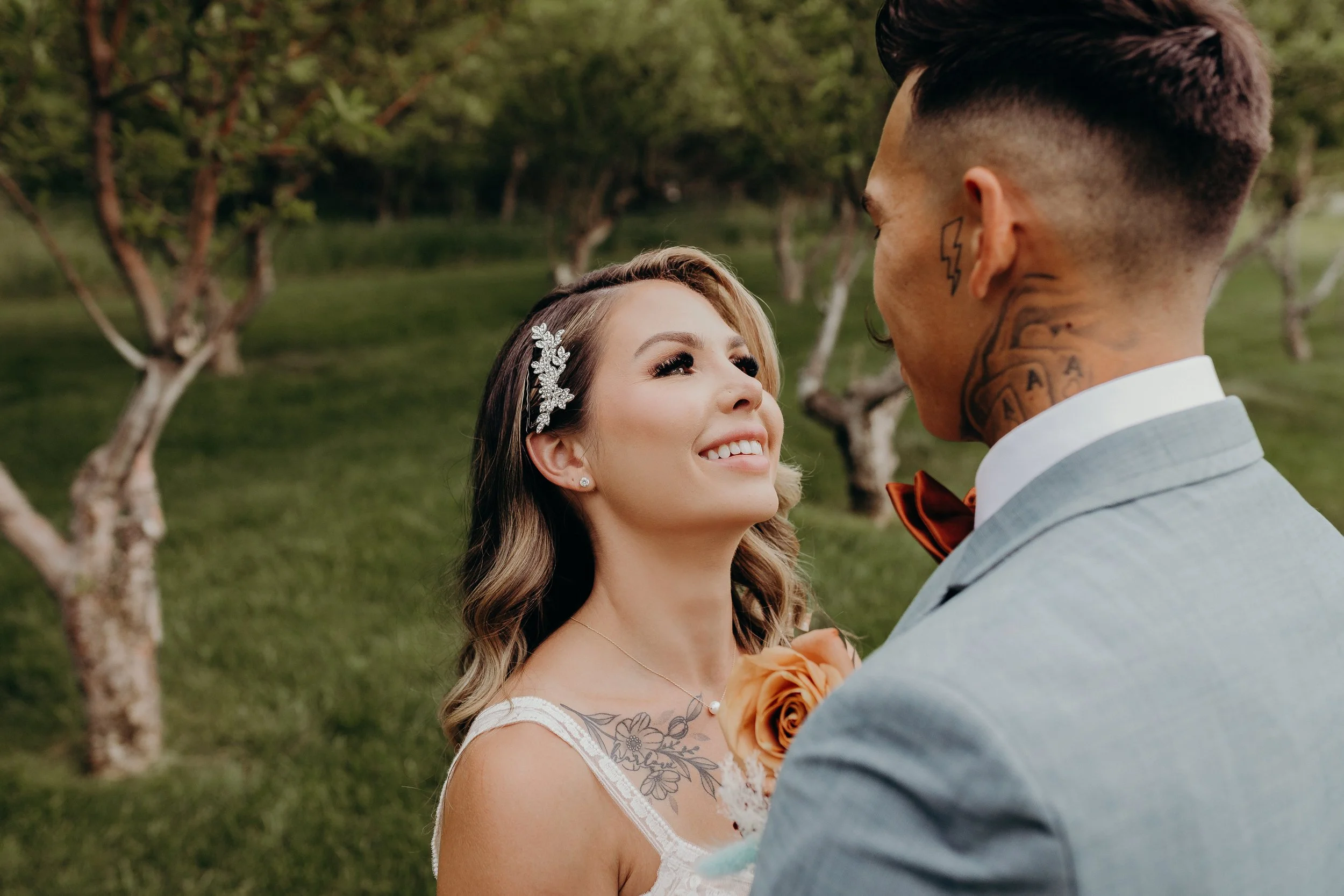 Bride looking up into groom's eyes and smiling in an apple orchard