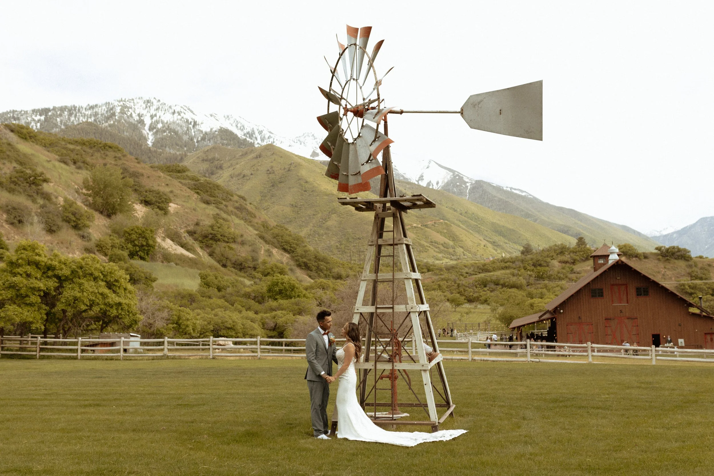 Bride and groom standing in front of a windmill with mountain views in the background