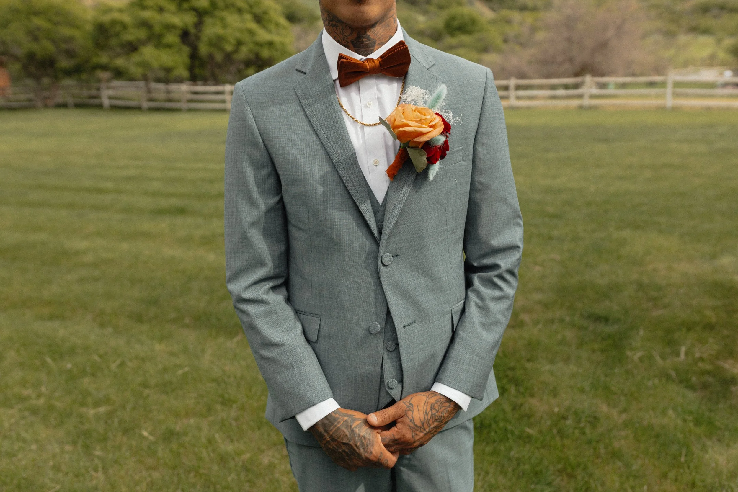 Groom's grey tux with an orange rose on his boutonniere 