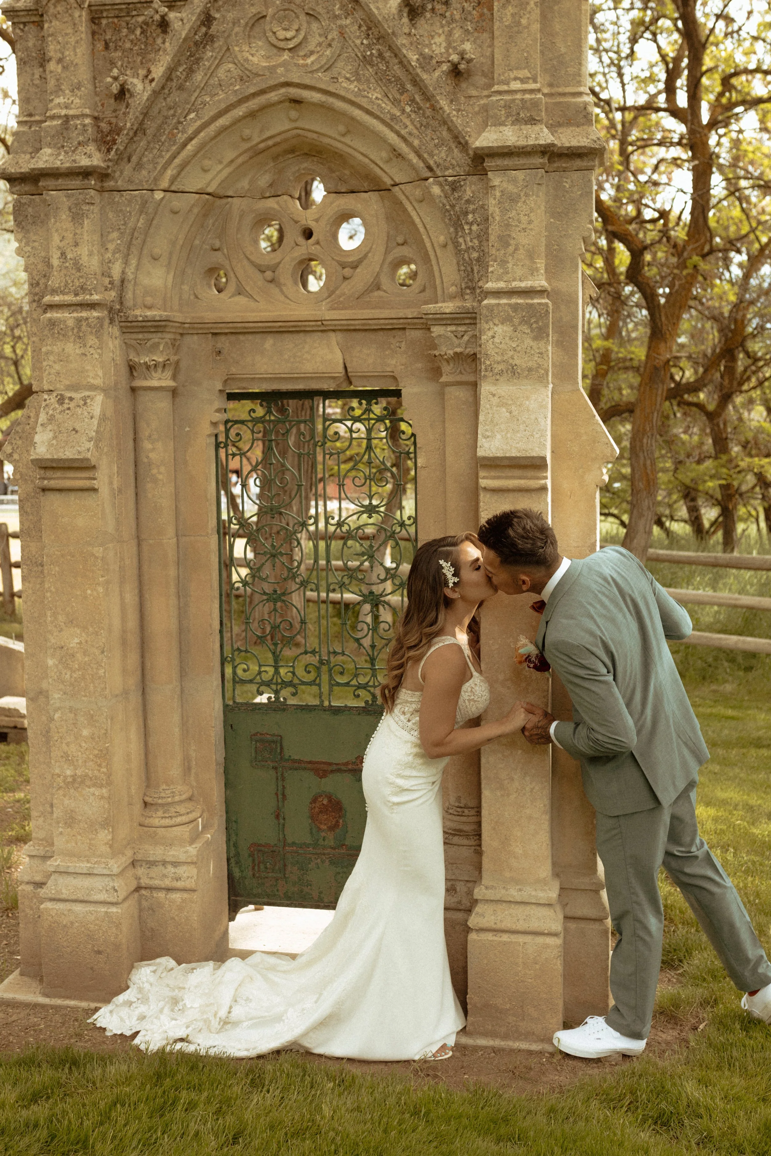 Bride and groom kissing around an imported Italian Arch made of stone