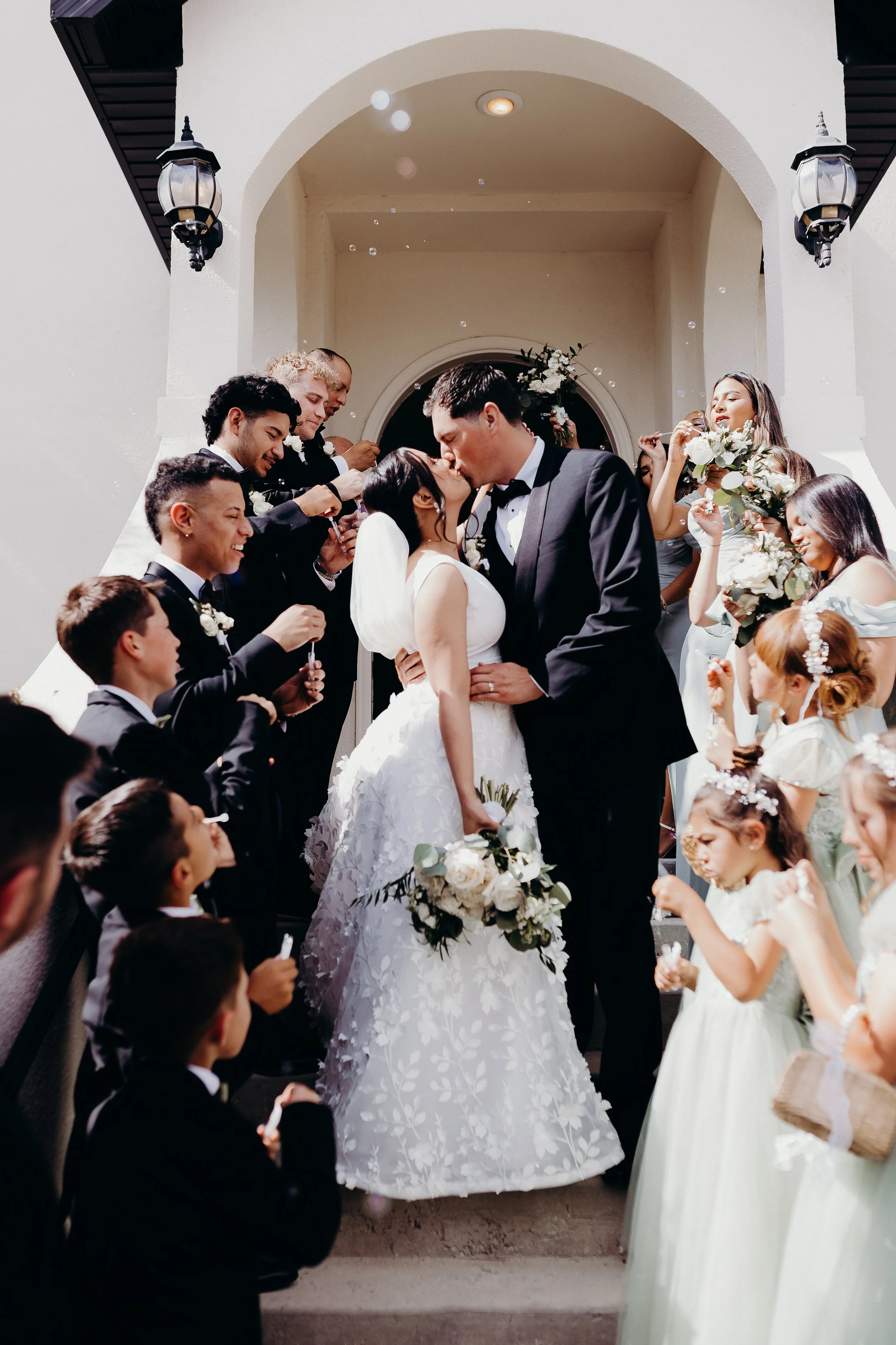 Bride and groom kissing surrounded by bridesmaids and groomsmen