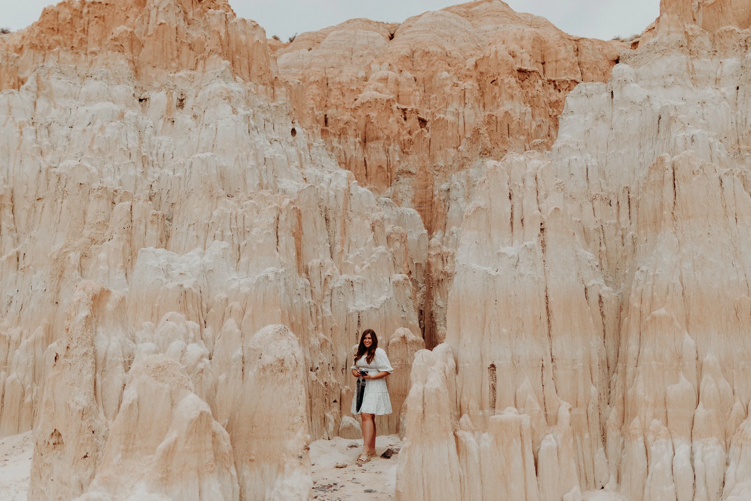 Woman standing in rock formations in a white dress
