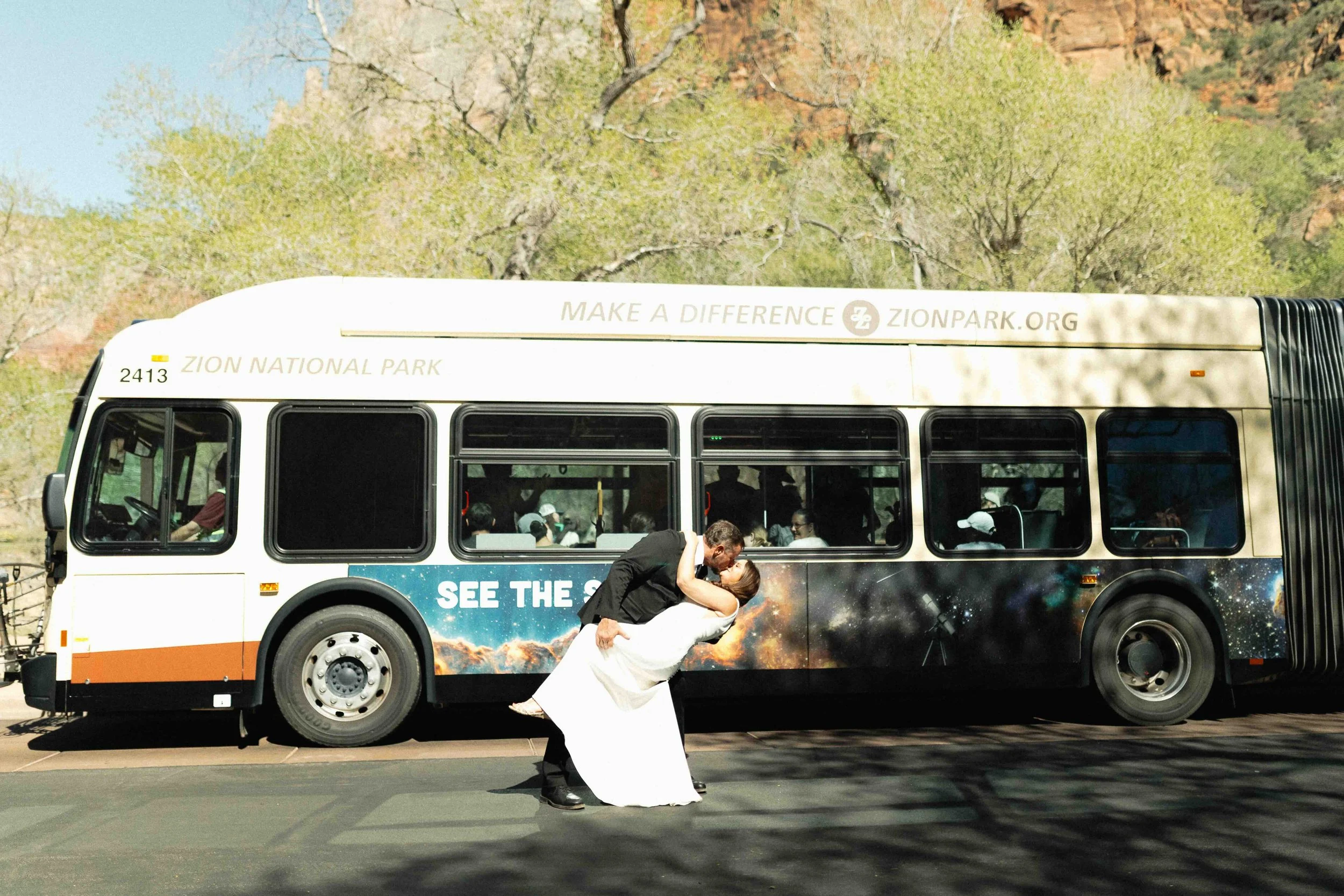 Couple dipping and kissing in front of a shuttle in Zion National Park.