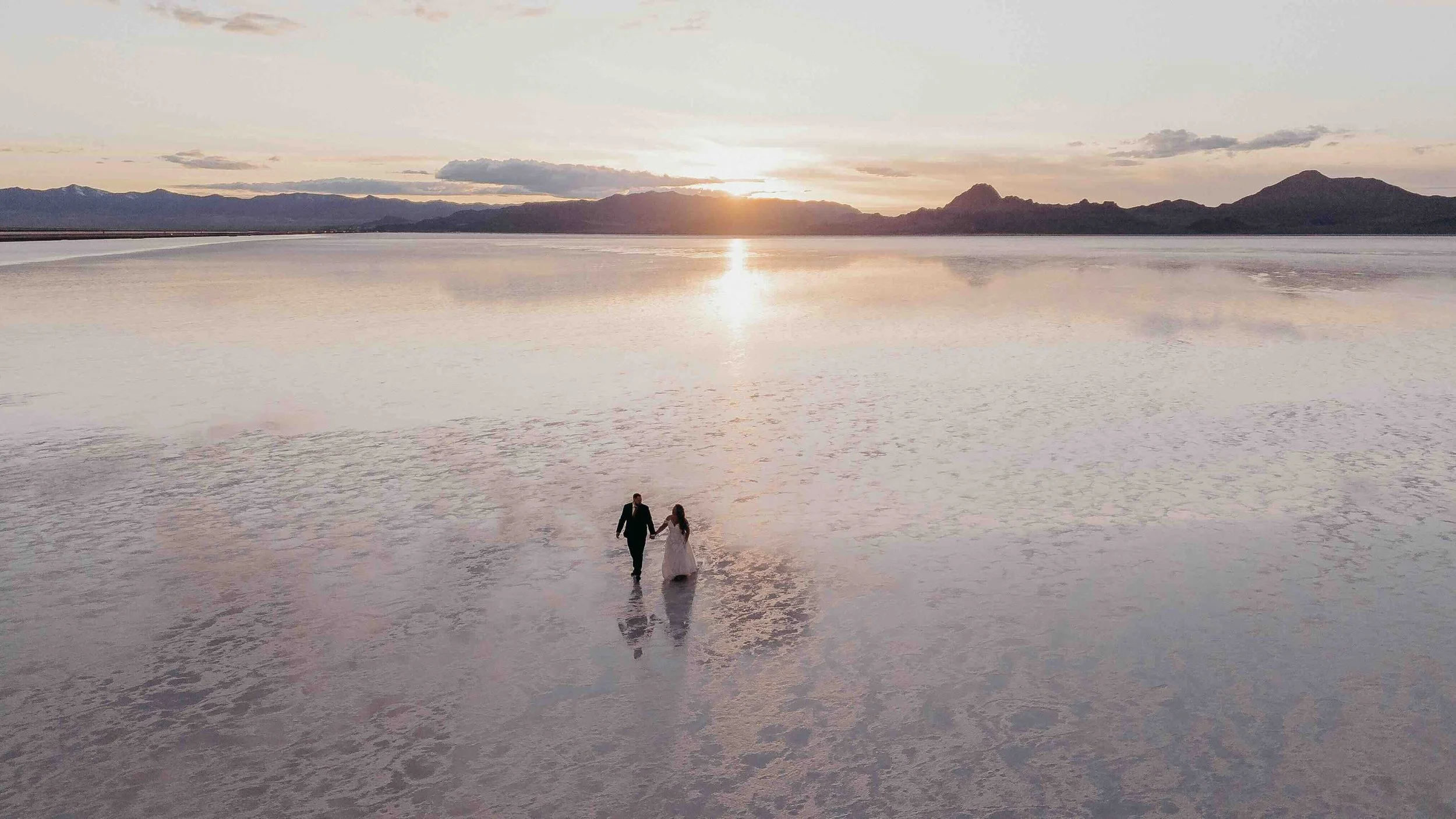Husband and wife holding hands in front of salt flats in Utah
